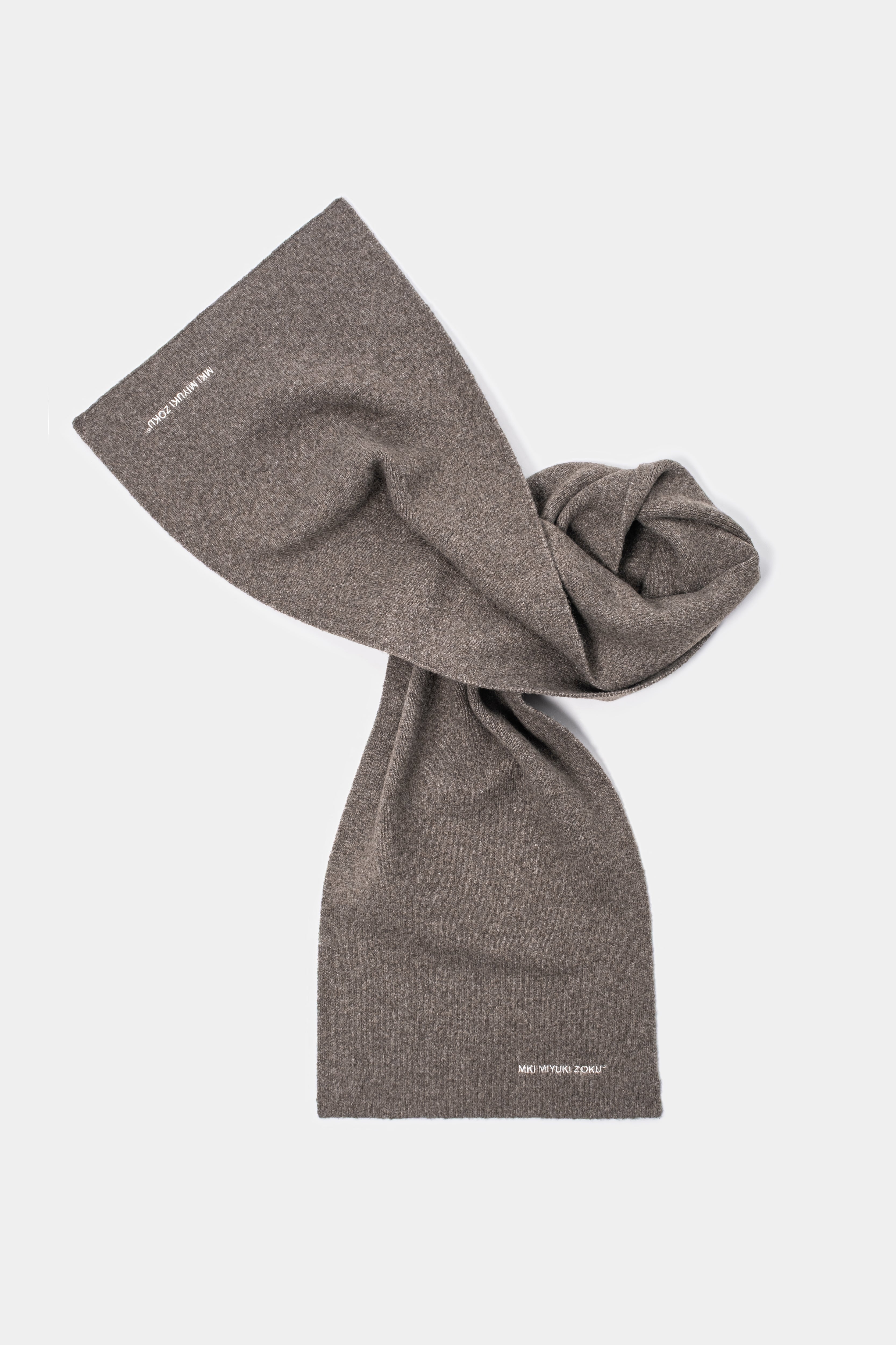 MKI MIYUKI ZOKU Double Knit Scarf in Brown – knotted flat lay showing the compact double knit and embroidered logo at each end