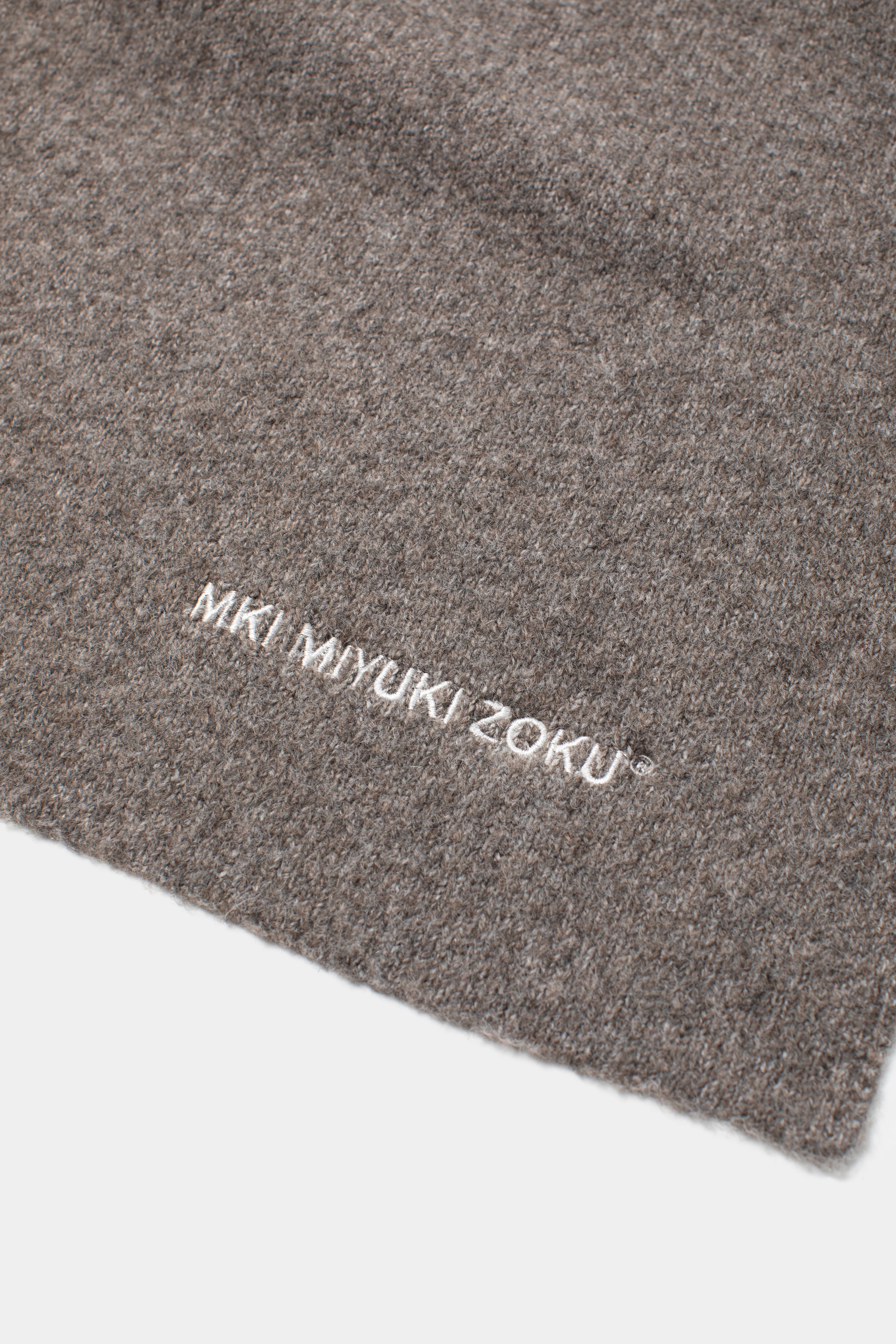 Close-up of the white MKI MIYUKI ZOKU logo embroidered on the Brown double knit wool blend