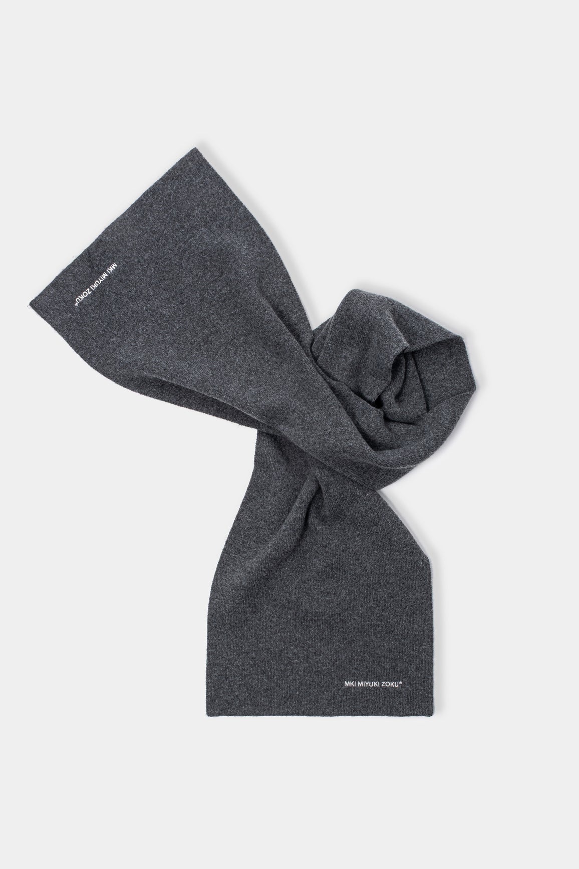 MKI MIYUKI ZOKU Double Knit Scarf in Charcoal – knotted flat lay showing the compact double knit and embroidered logo at each end