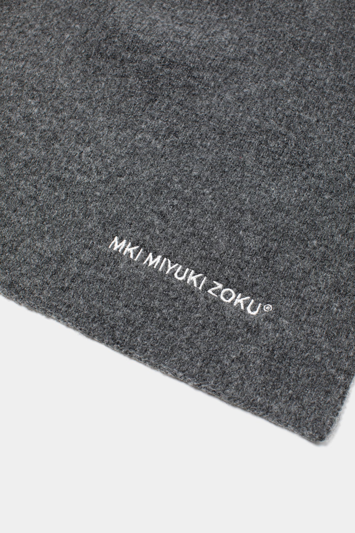 Close-up of the white MKI MIYUKI ZOKU logo embroidered on the Charcoal double knit wool blend
