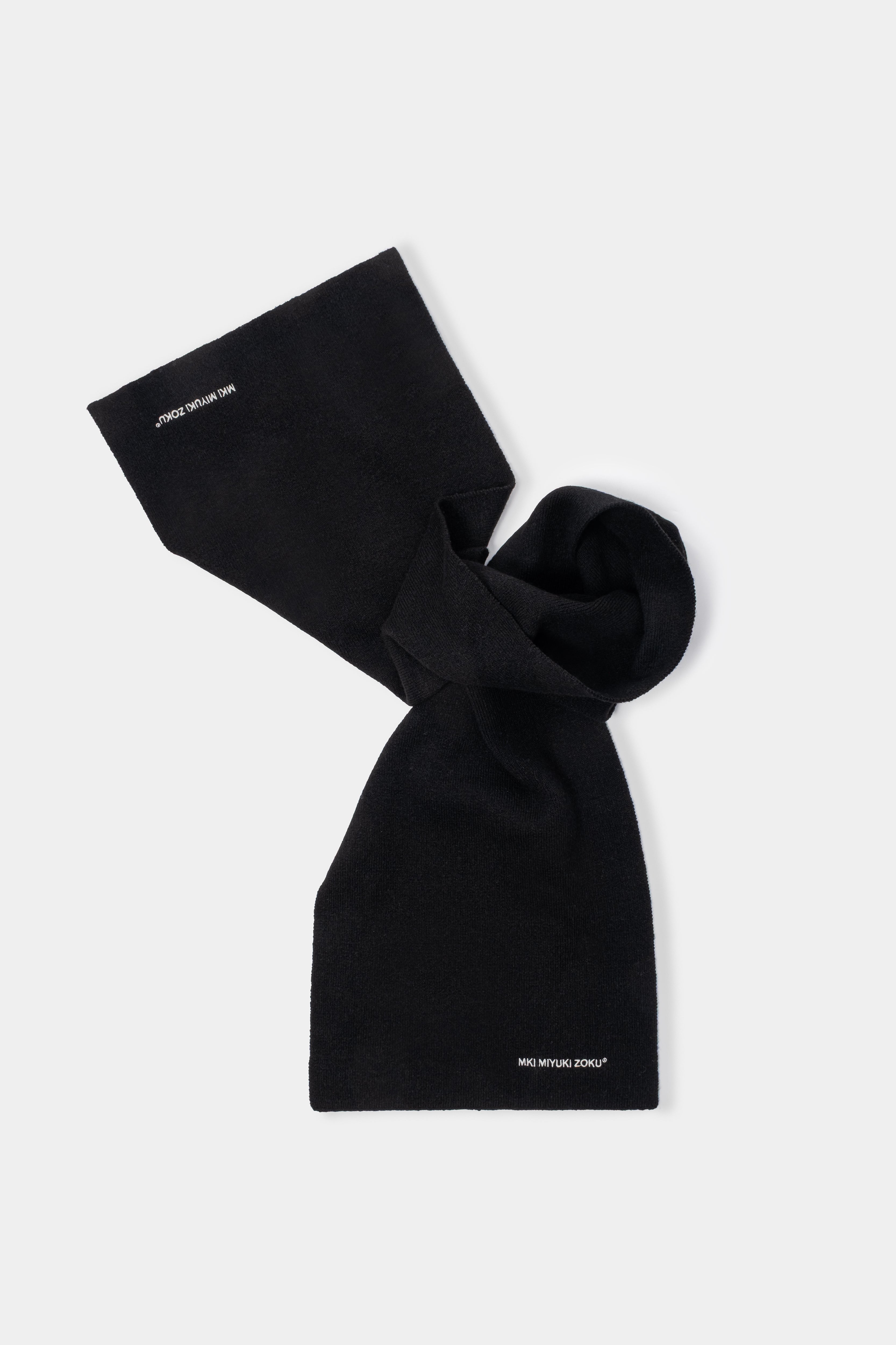 MKI MIYUKI ZOKU Double Knit Scarf in Black – knotted flat lay showing the compact double knit and embroidered logo at each end