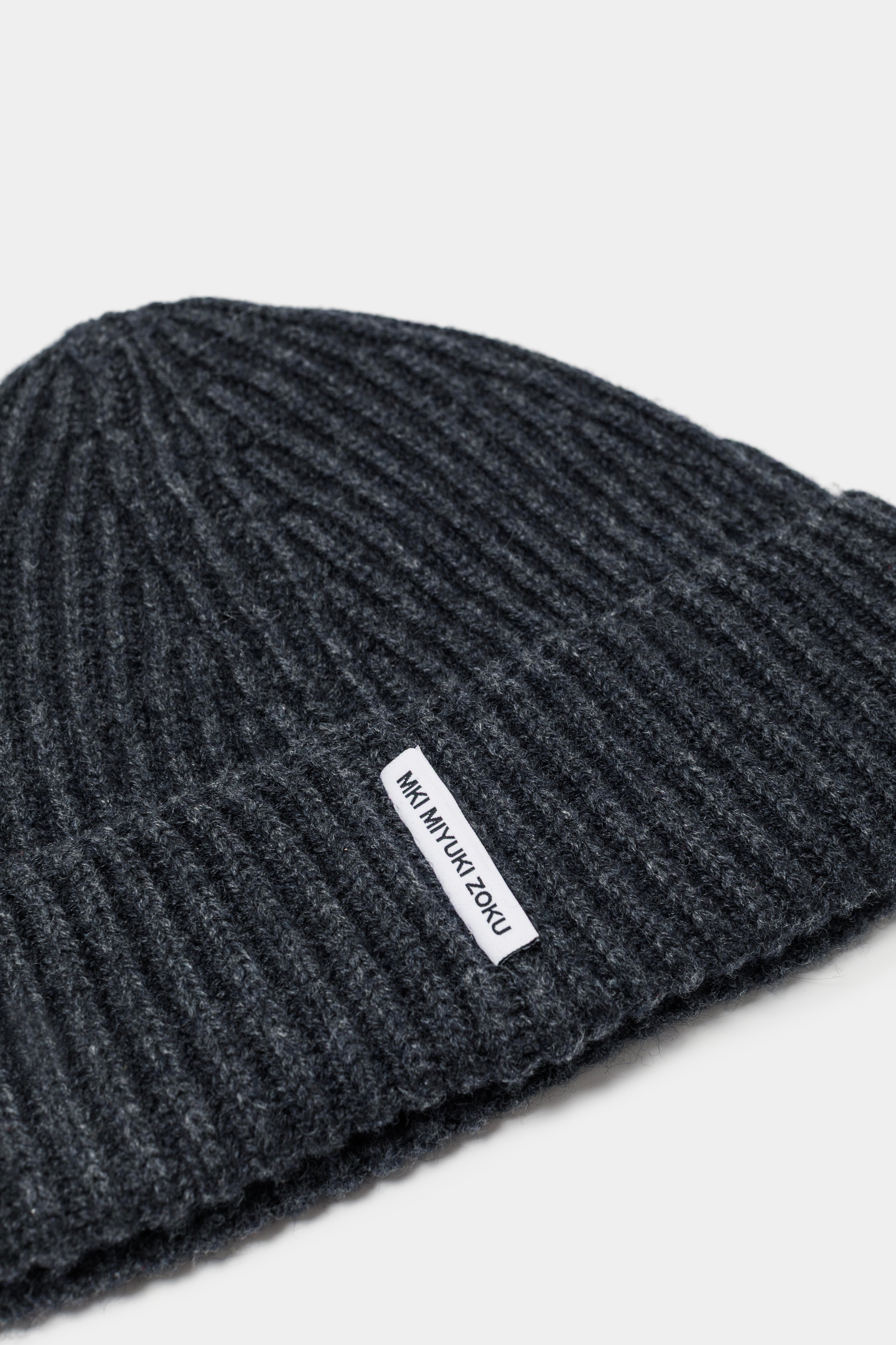 Close-up of the woven MKI MIYUKI ZOKU tag and heavy rib knit on the Charcoal cashmere beanie