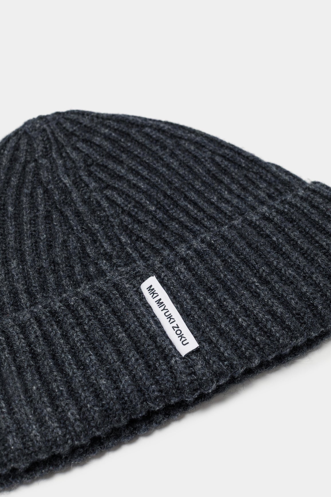 Close-up of the woven MKI MIYUKI ZOKU tag and heavy rib knit on the Charcoal cashmere beanie