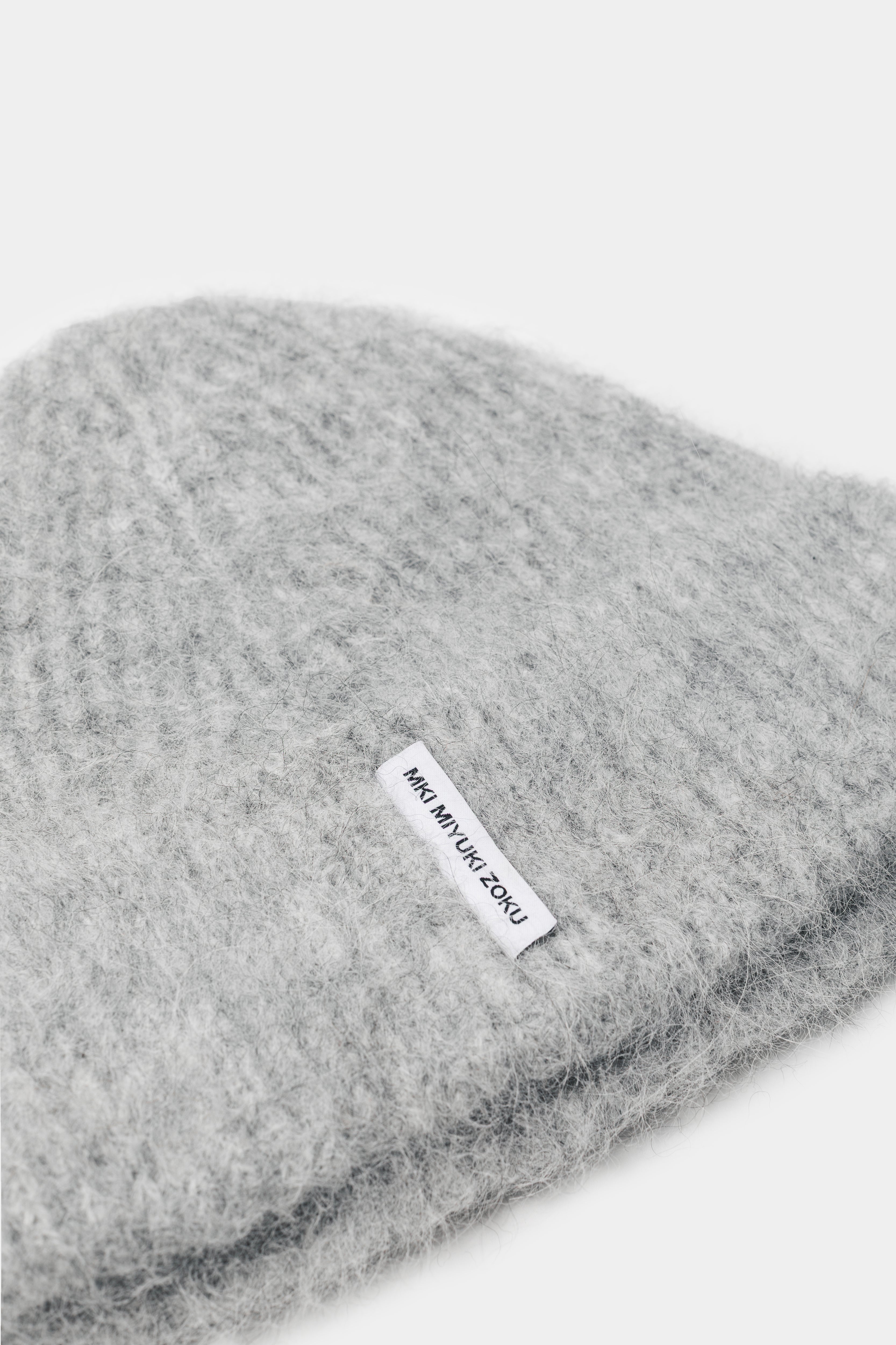 Close-up of the woven MKI MIYUKI ZOKU tag and fuzzy alpaca knit on the Light Grey beanie