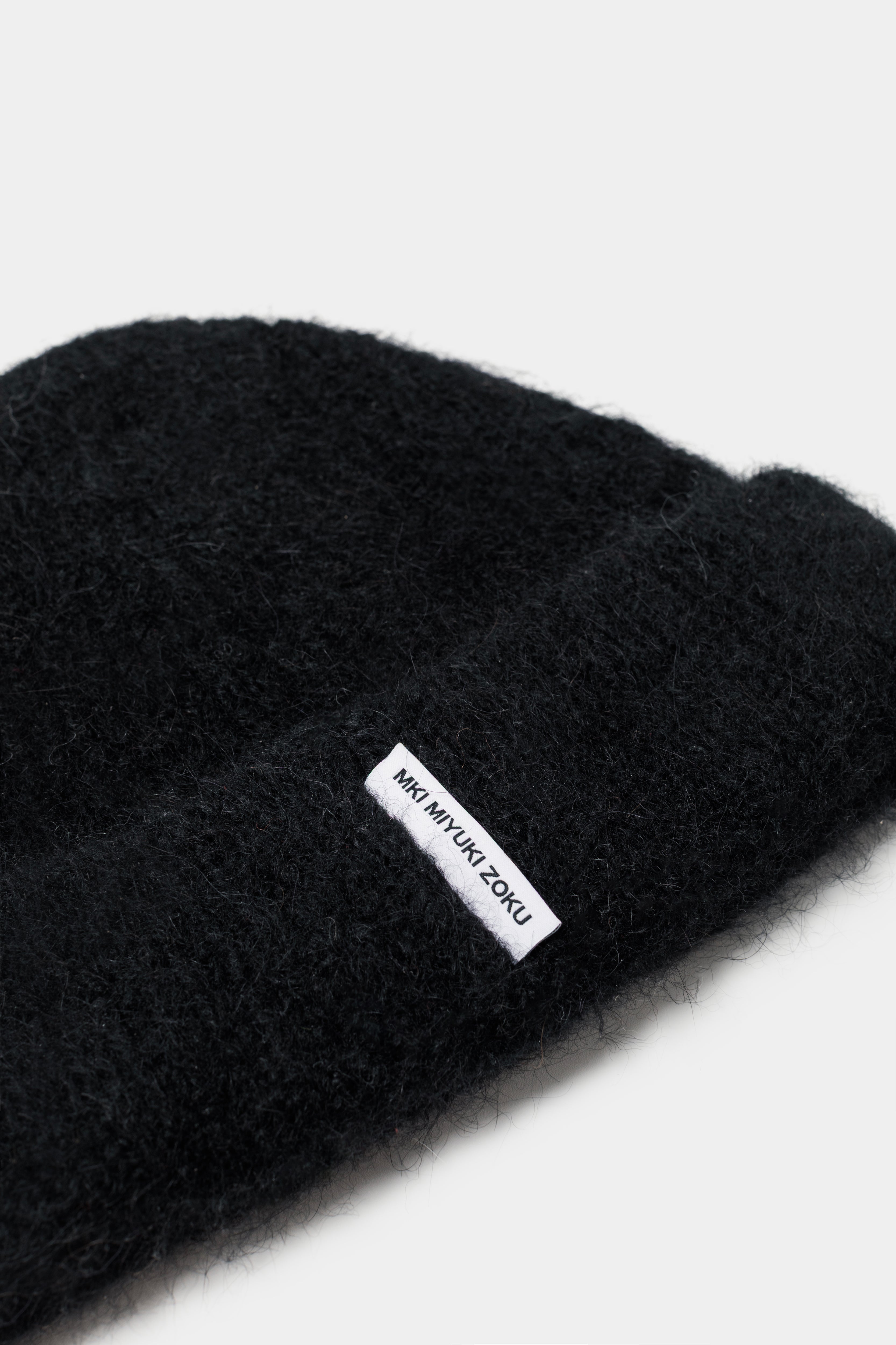 Close-up of the woven MKI MIYUKI ZOKU tag and fuzzy alpaca knit on the Black beanie