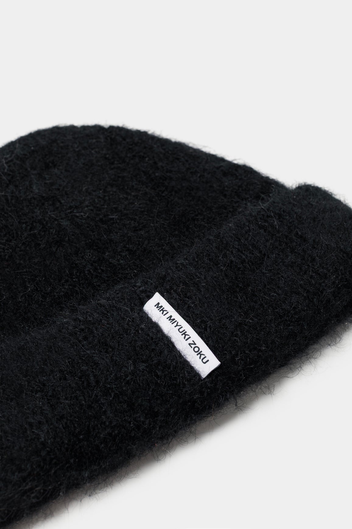 Close-up of the woven MKI MIYUKI ZOKU tag and fuzzy alpaca knit on the Black beanie
