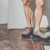 Person wearing beige trainers standing on a tiled floor