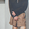 Person wearing a black long sleeved top and brown shorts