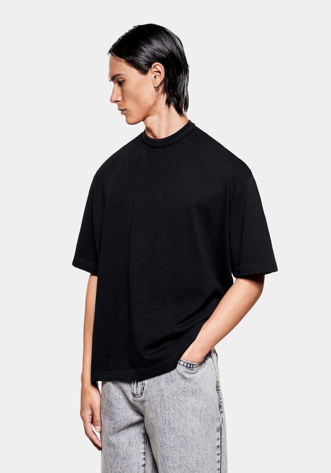 Three-quarter view of the boxy black slub T-shirt showing the dropped shoulders and short sleeves
