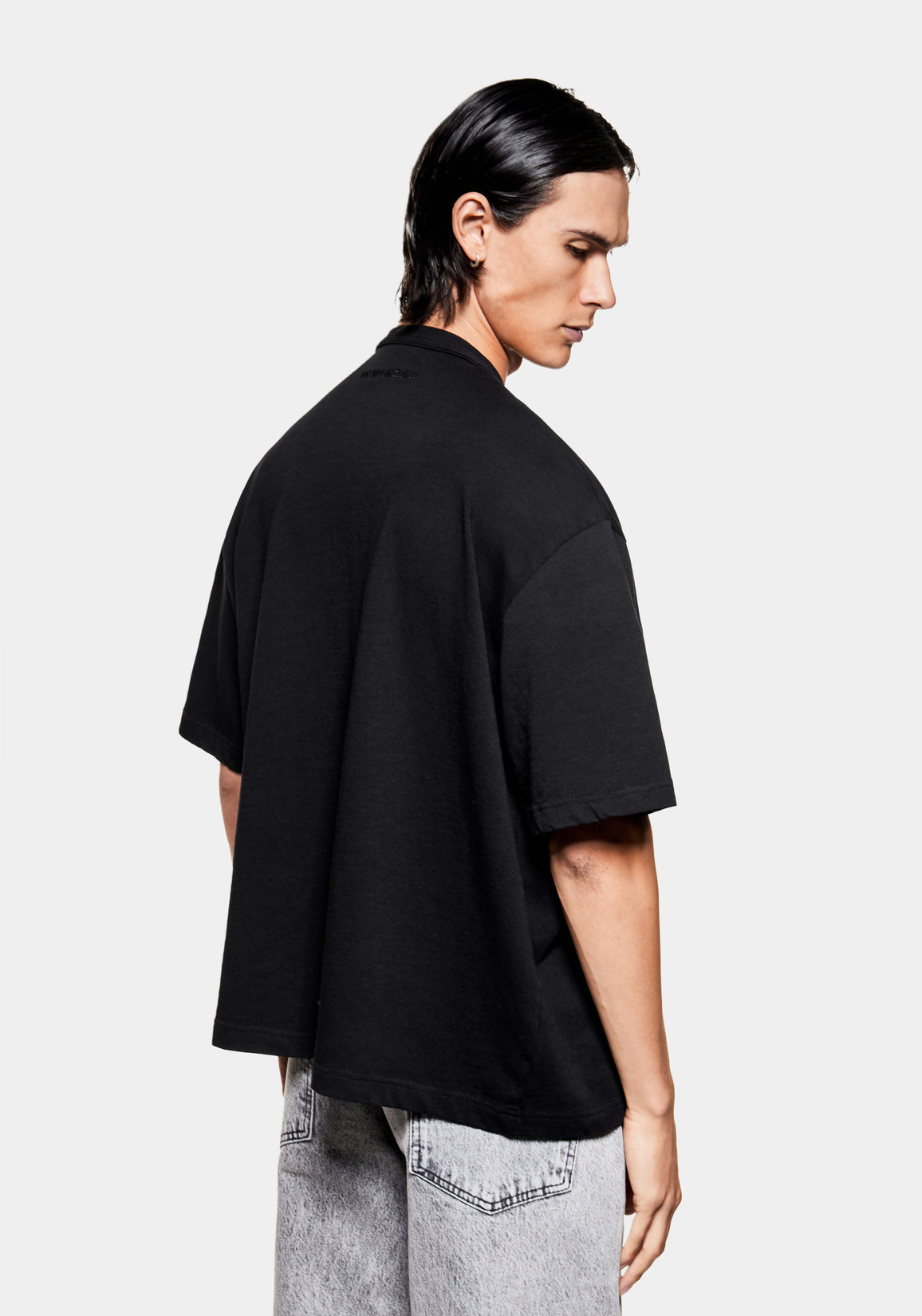 Back view of the black slub T-shirt on the model, showing the relaxed box fit