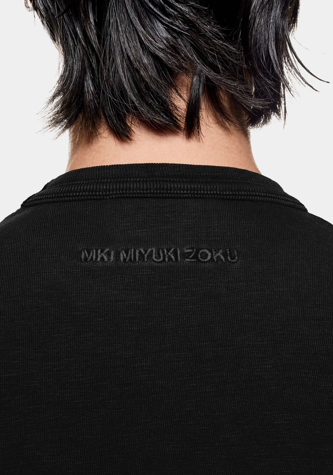 Close-up of the tonal black MKI MIYUKI ZOKU logo embroidered below the back neck