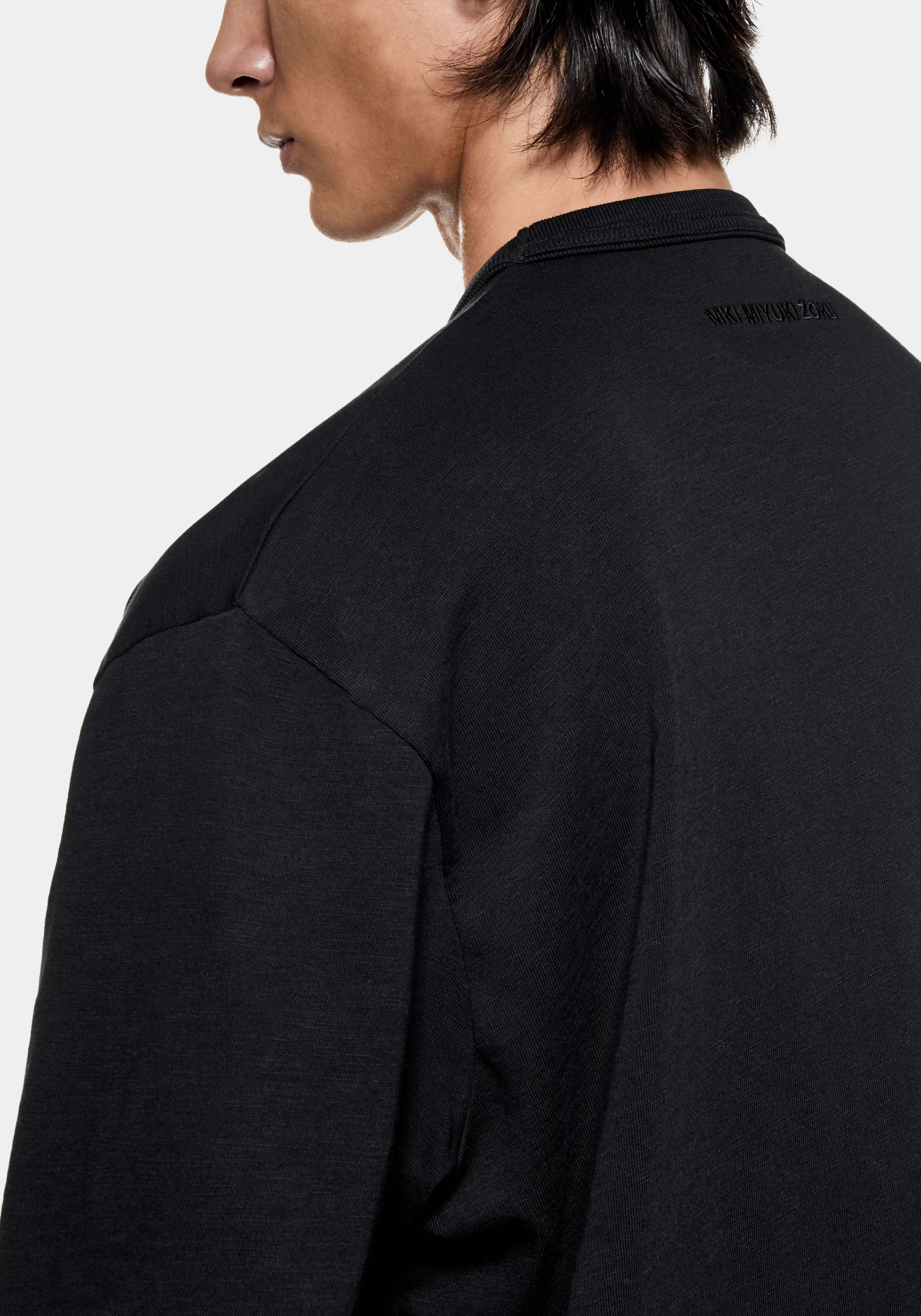 Close-up of the dropped shoulder seam and textured slub jersey on the black T-shirt