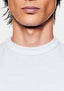 Close-up of the ribbed crew neckline on the white slub cotton jersey