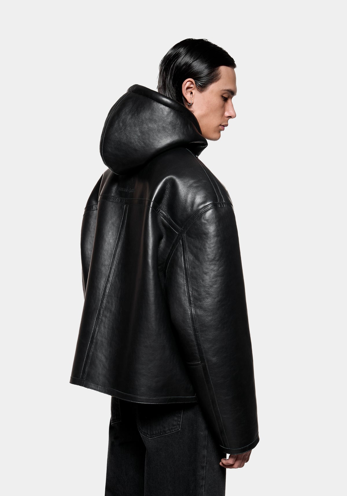 Person wearing a black leather hooded jacket viewed from the side