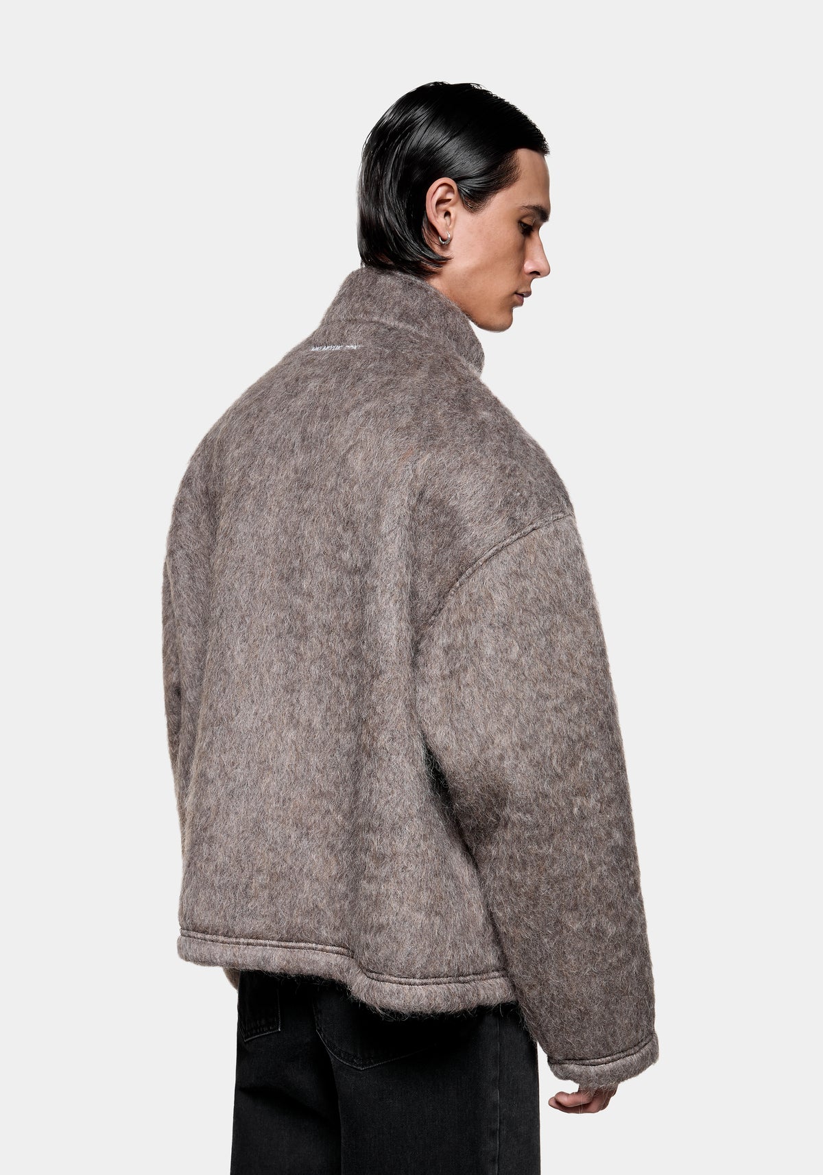 Person wearing a brown textured wool blend jacket with a high collar viewed from the side