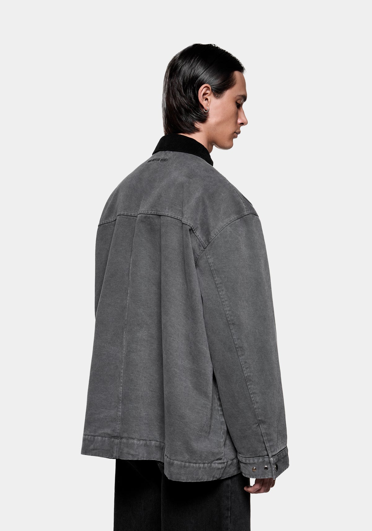 Person wearing a grey denim jacket with a black corduroy collar from the back