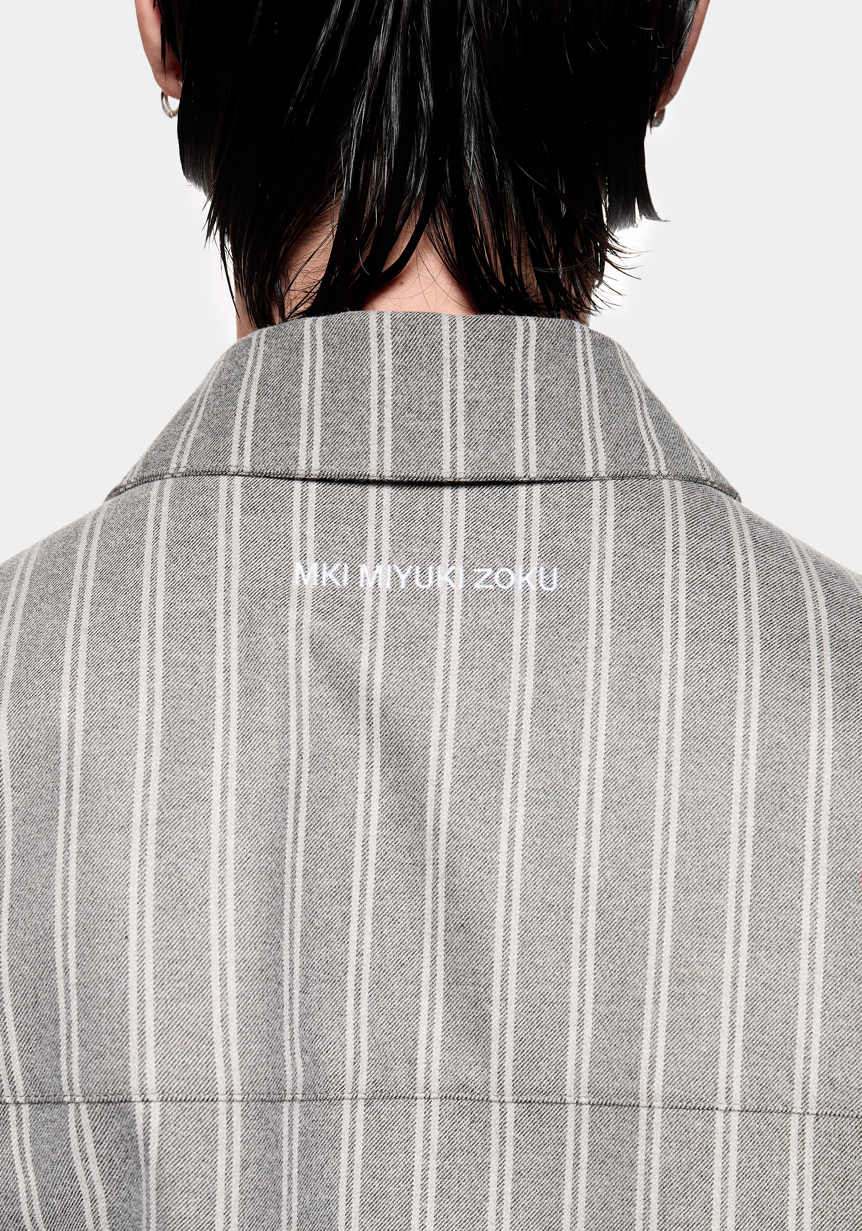 Close-up of the MKI MIYUKI ZOKU logo embroidery at the collar on the Box Dress Shirt in Grey Stripe