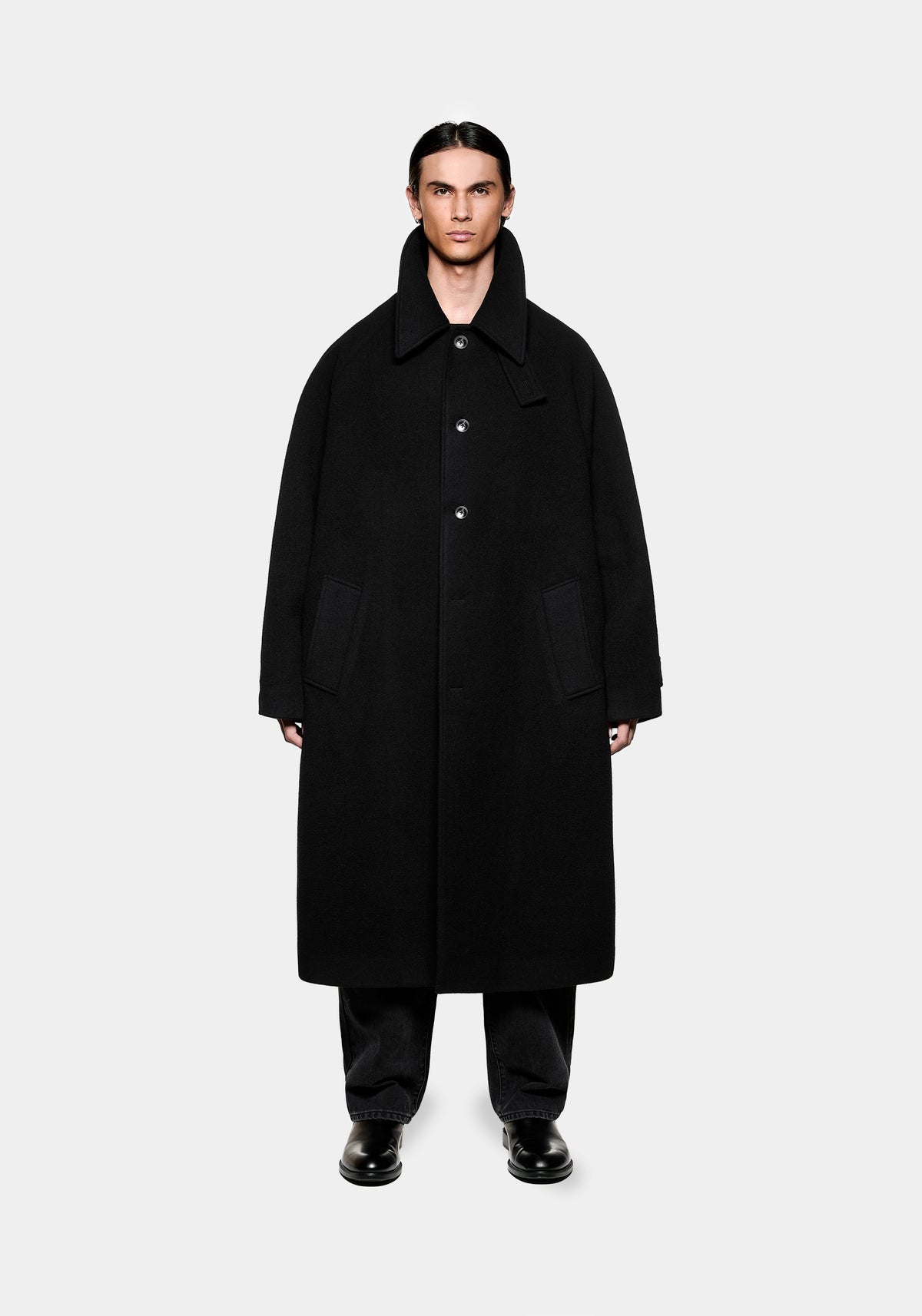 Model wearing a black wool overcoat with a high collar and button fastening