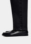 Close-up of the straight hem of the Black Wash jeans falling over black loafers