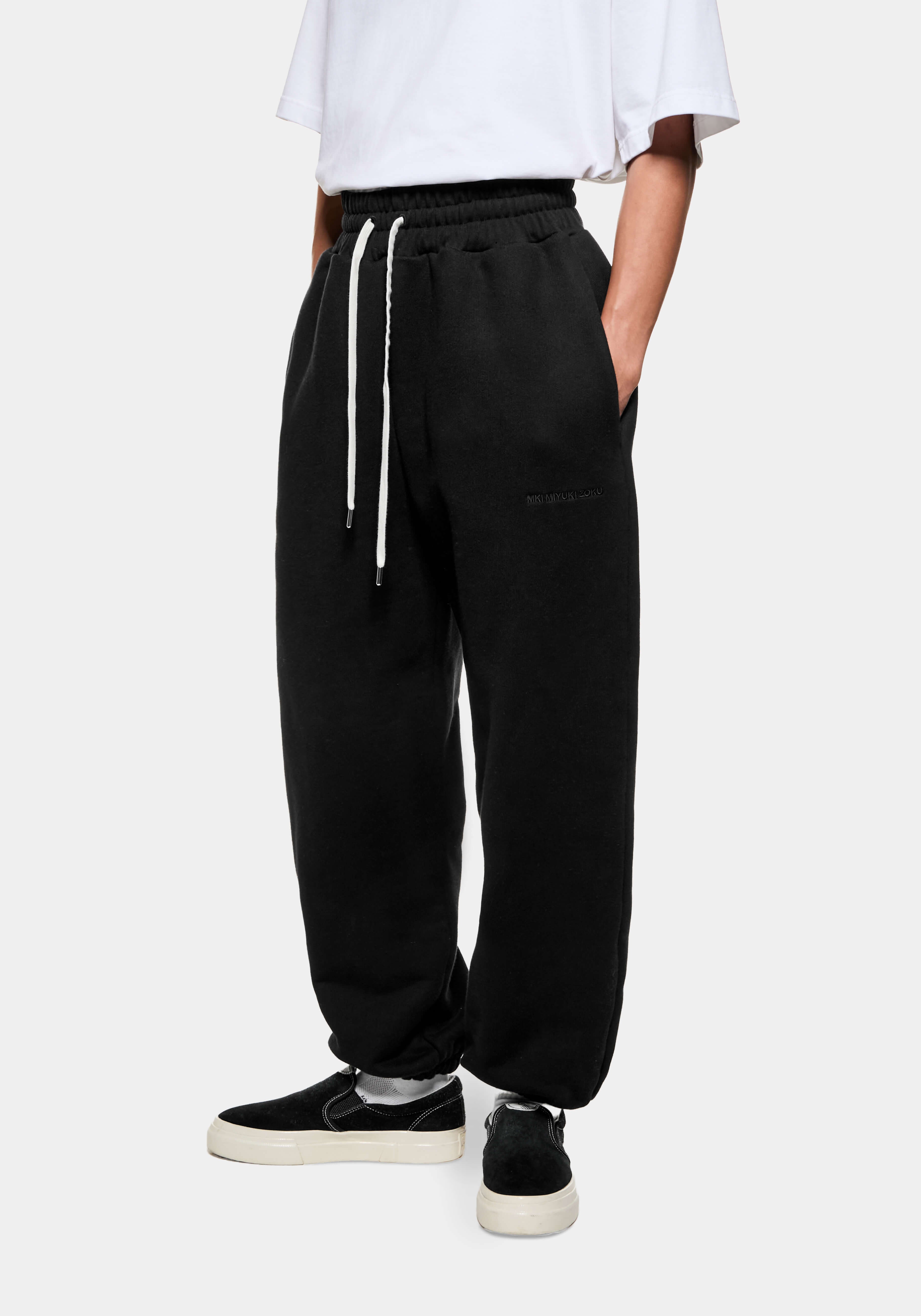 Front three-quarter view of the Black Superweight Joggers showing the heavy drape and cuffed hems over black slip ons