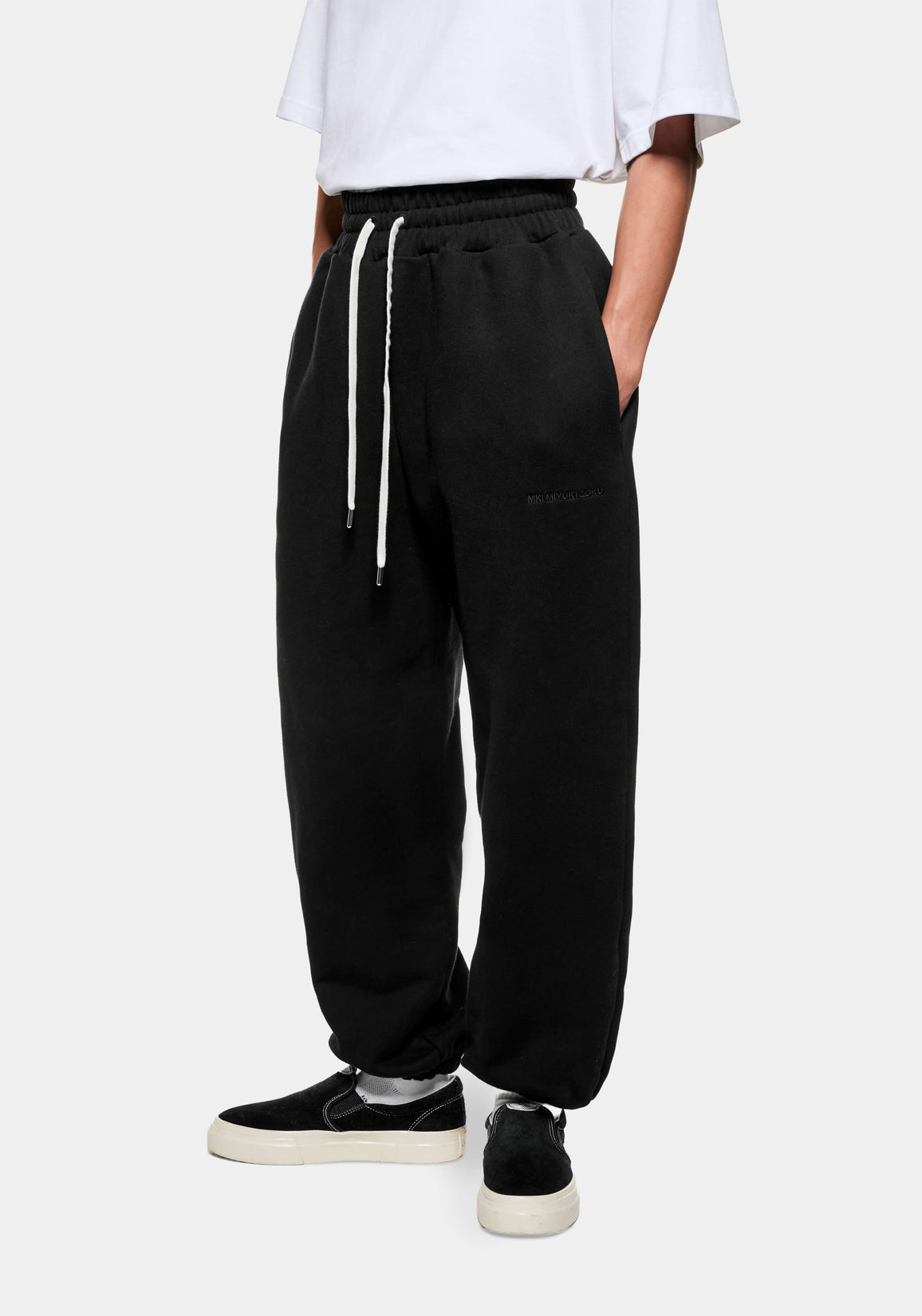 Front three-quarter view of the Black Superweight Joggers showing the heavy drape and cuffed hems over black slip ons