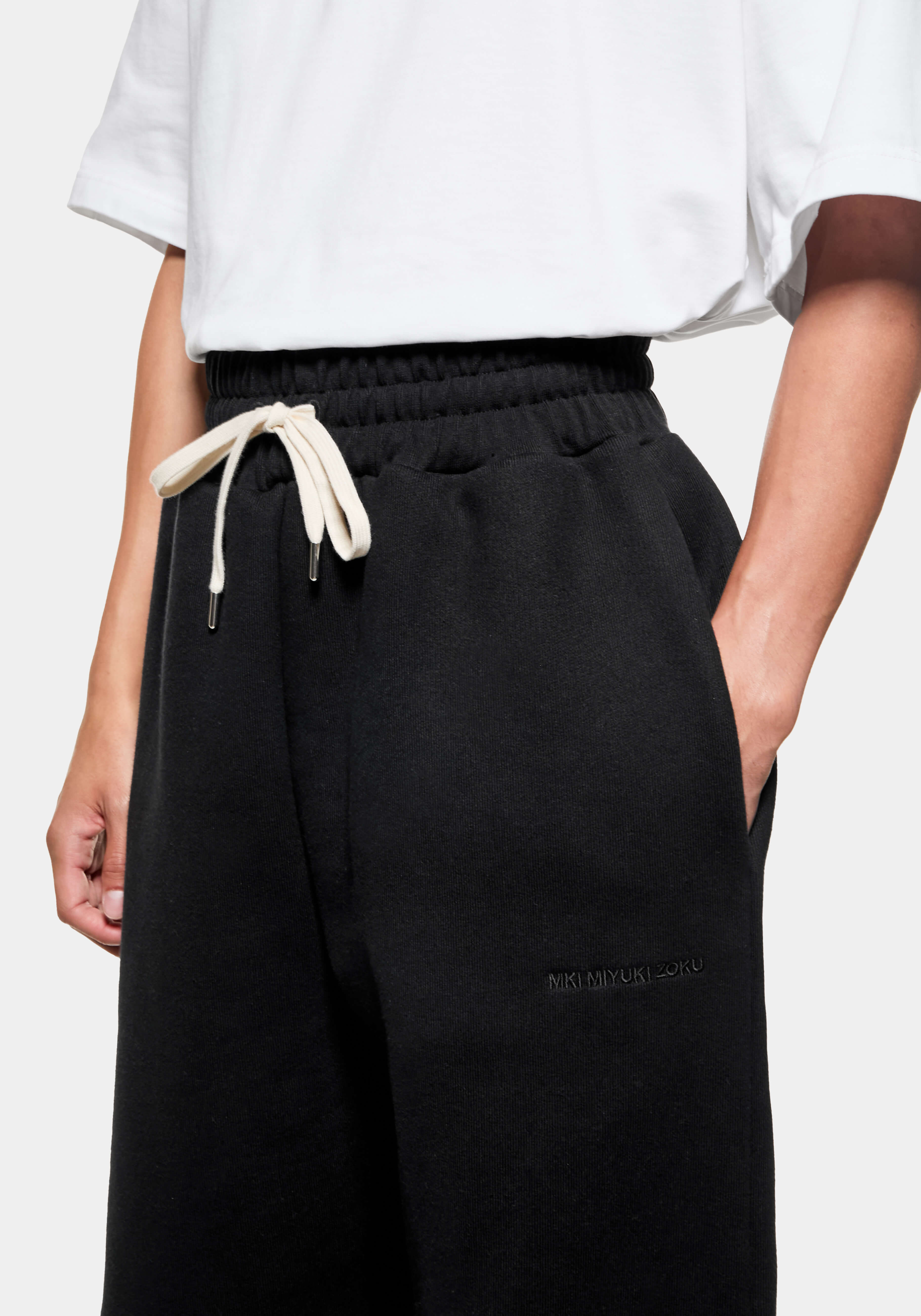 Close-up of the side entry pocket and tonal logo embroidery at the front thigh of the Black joggers