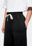 Close-up of the side entry pocket and tonal logo embroidery at the front thigh of the Black joggers