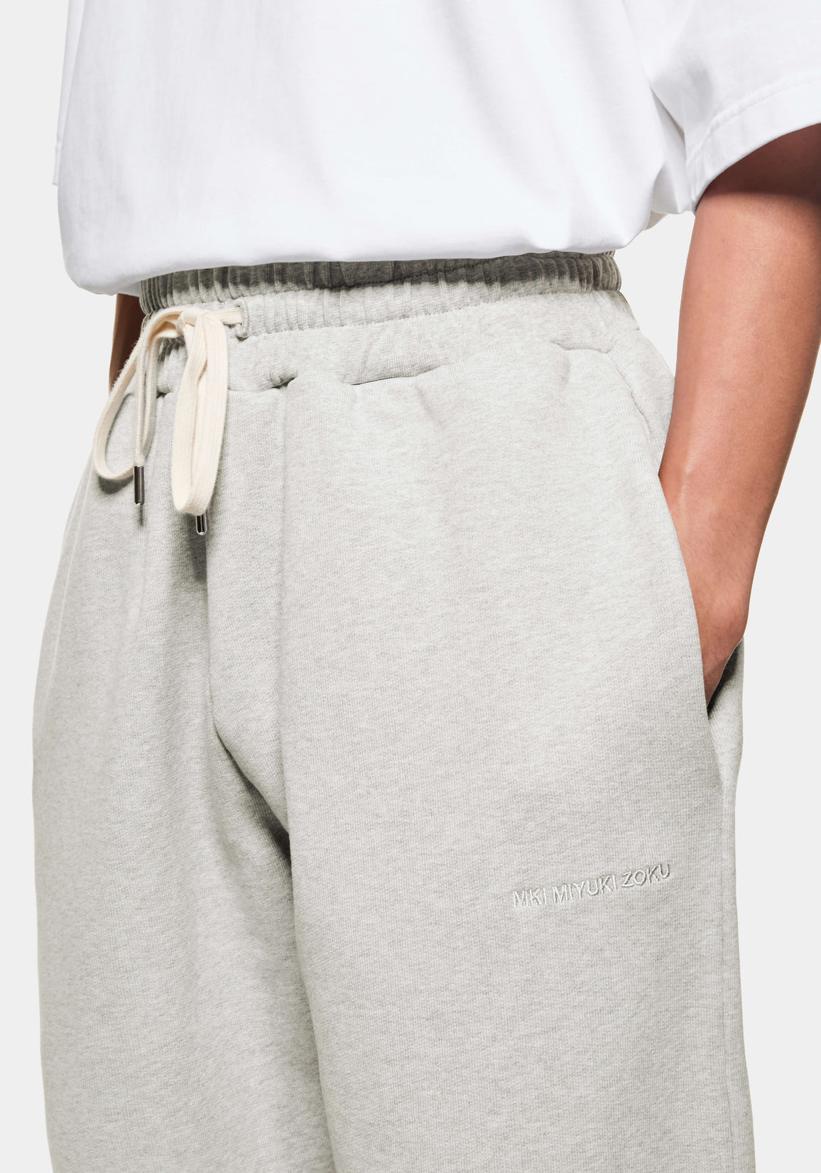 Close-up of the side entry pocket and tonal logo embroidery at the front thigh of the Oatmeal joggers