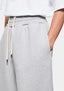 Close-up of the side entry pocket, front pleat and tonal logo embroidery on the Grey joggers