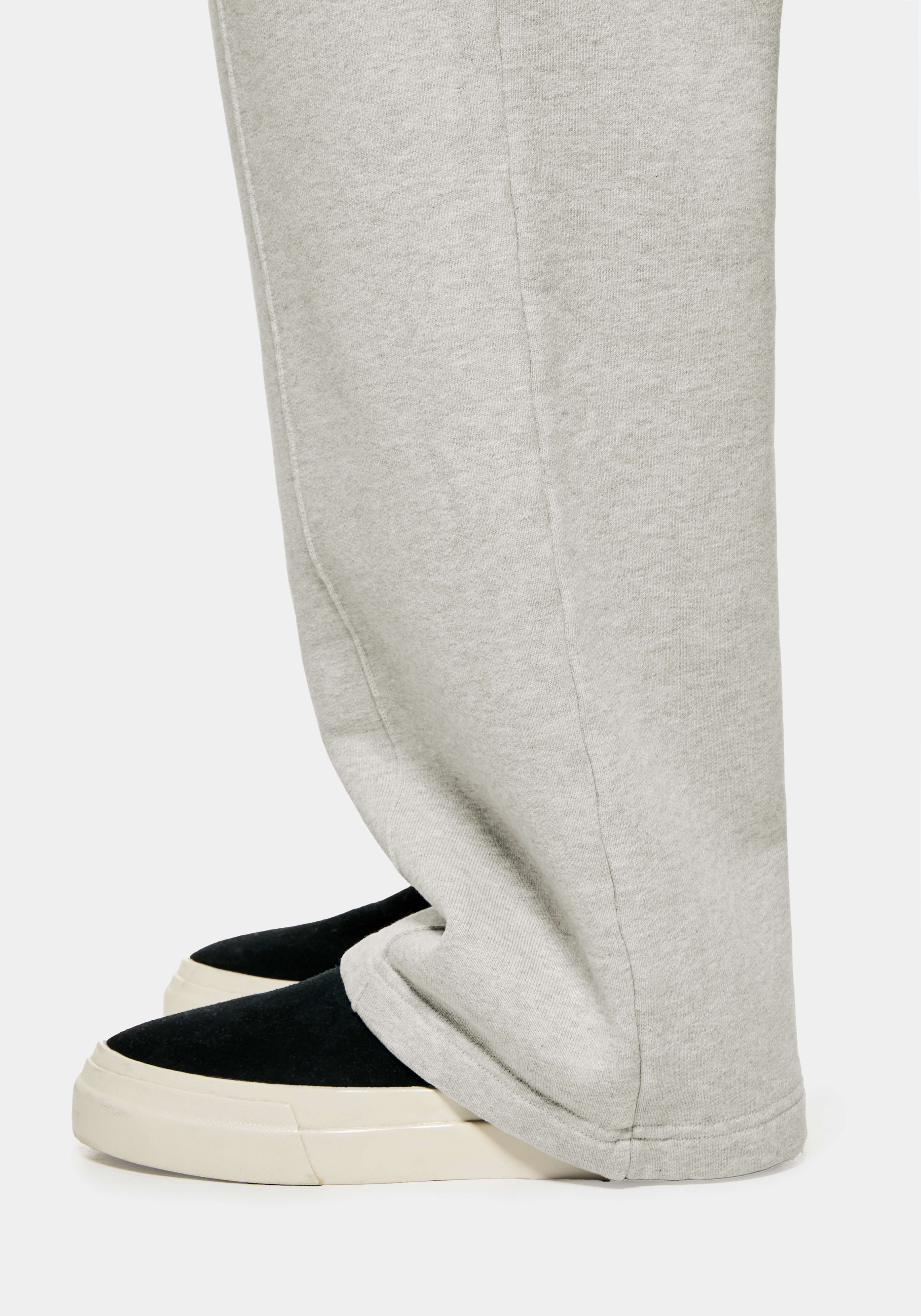 Close-up of the open hem of the Oatmeal joggers falling over black slip ons