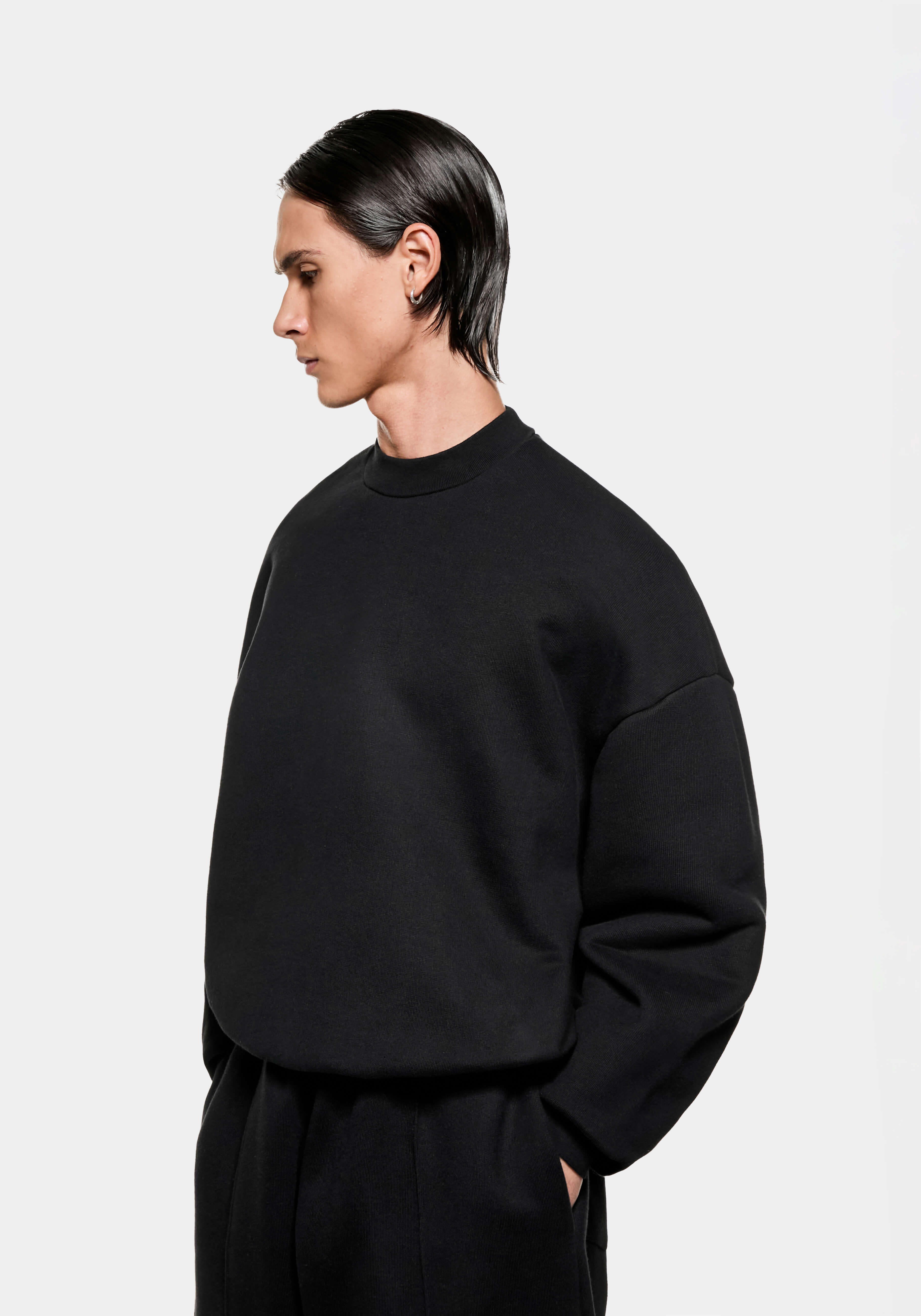 Side view of the oversized black Superweight crewneck showing the heavy drape and dropped shoulders