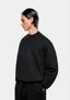 Side view of the oversized black Superweight crewneck showing the heavy drape and dropped shoulders