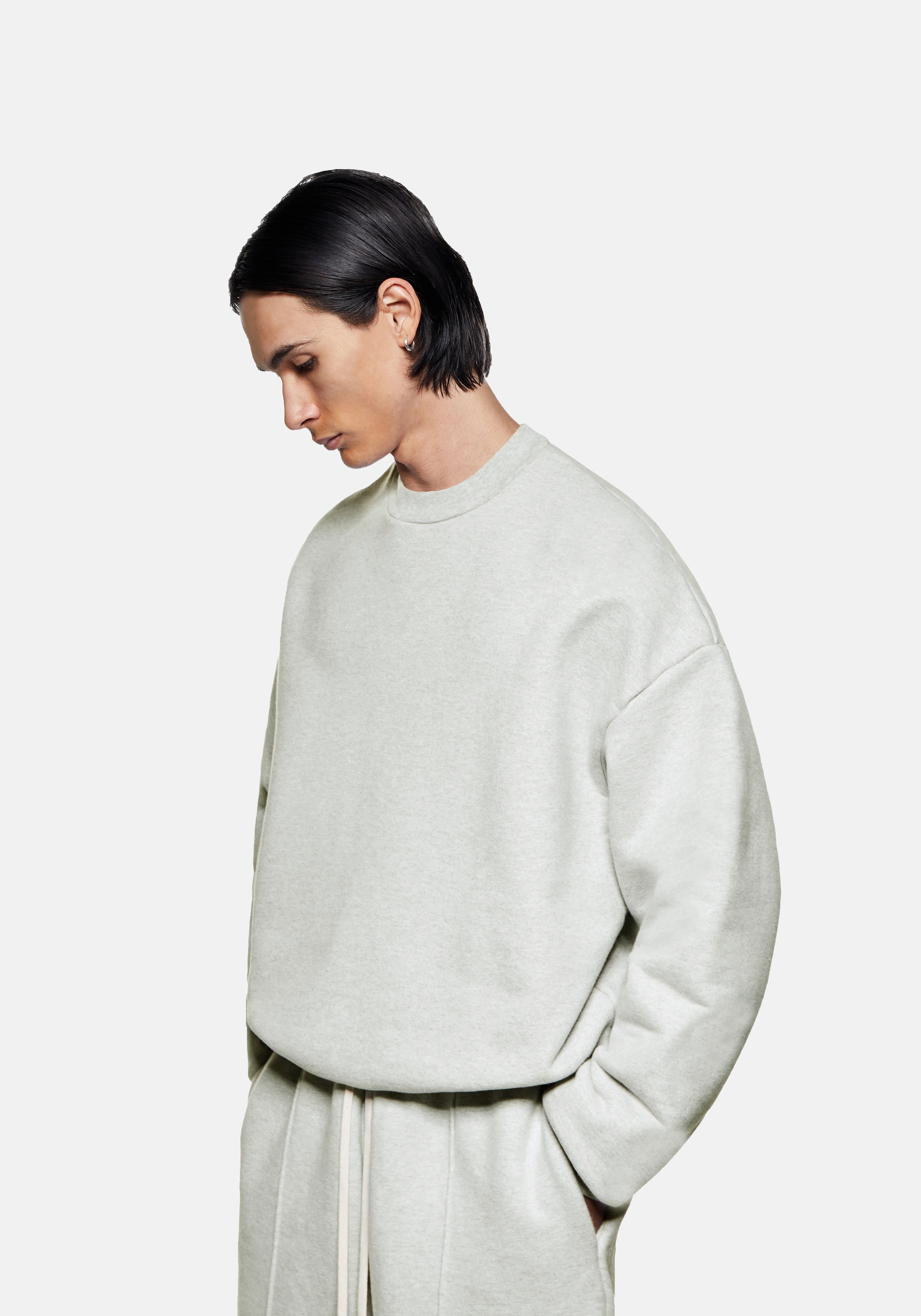Three-quarter view of the oversized oatmeal Superweight crewneck showing the heavy drape and dropped shoulders
