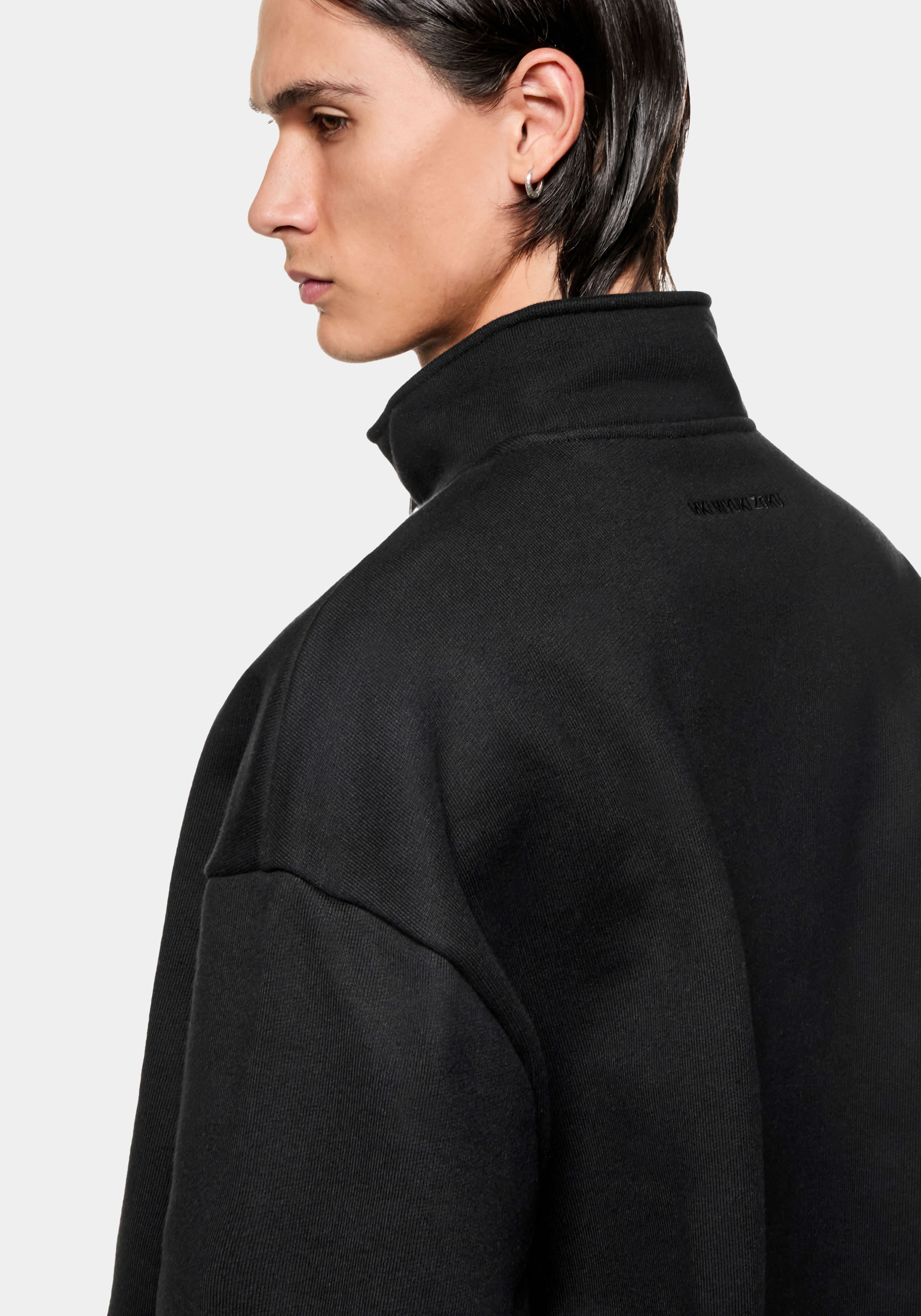 Side profile of the Black Quarter Zip showing the funnel neck and tonal logo below the collar