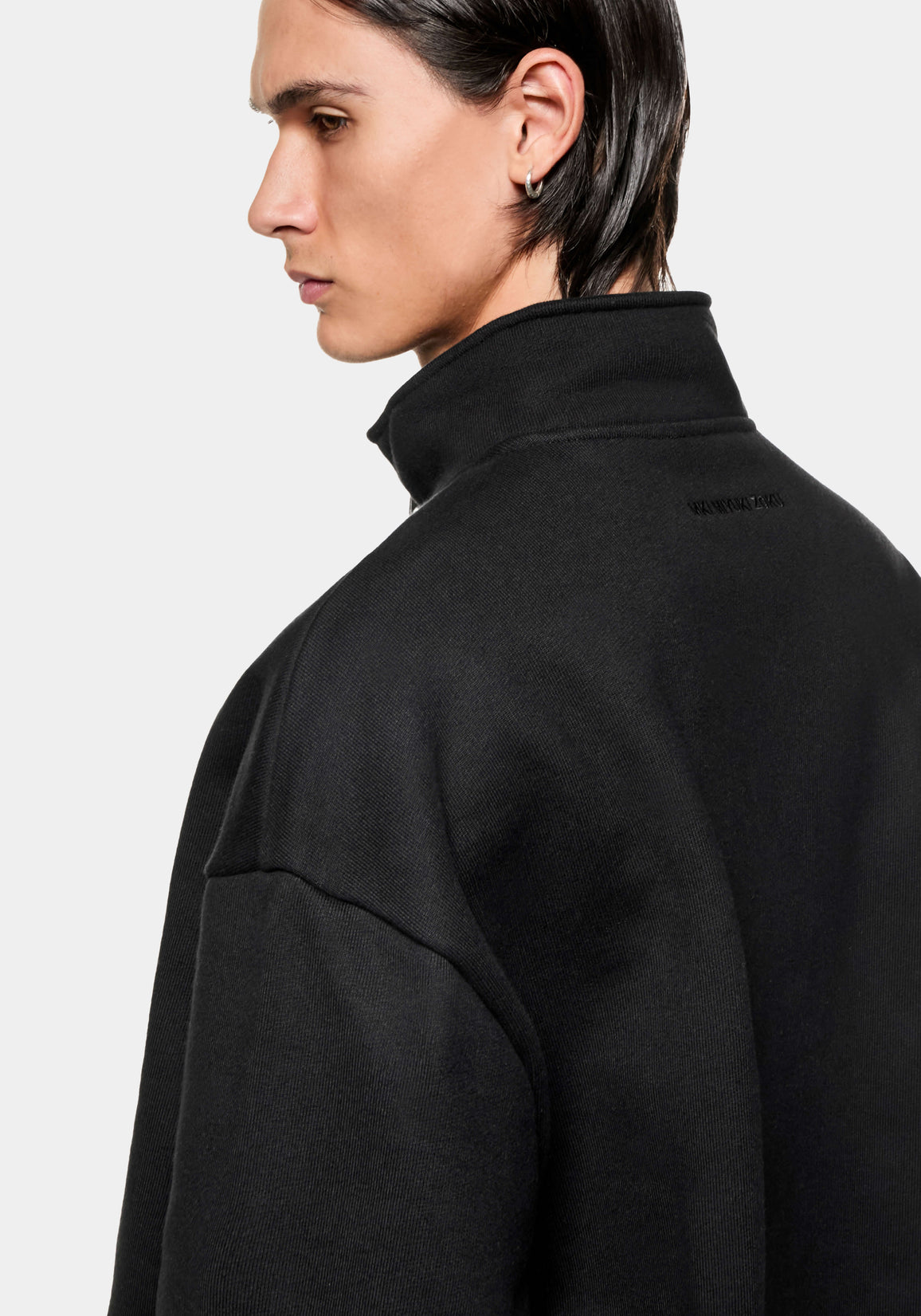 Side profile of the Black Quarter Zip showing the funnel neck and tonal logo below the collar