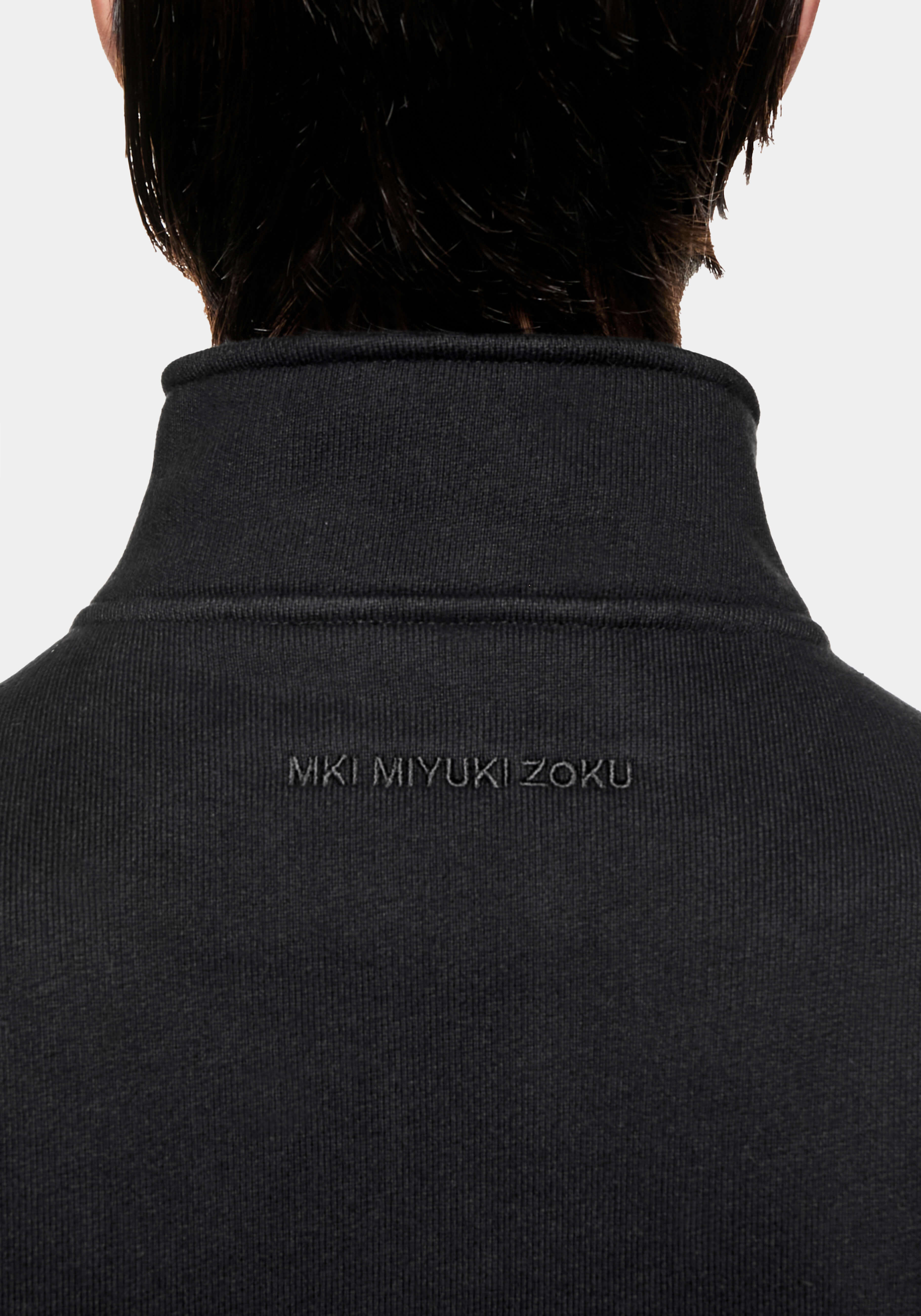 Back view of the funnel neck and tonal MKI MIYUKI ZOKU logo embroidery on the Black quarter zip