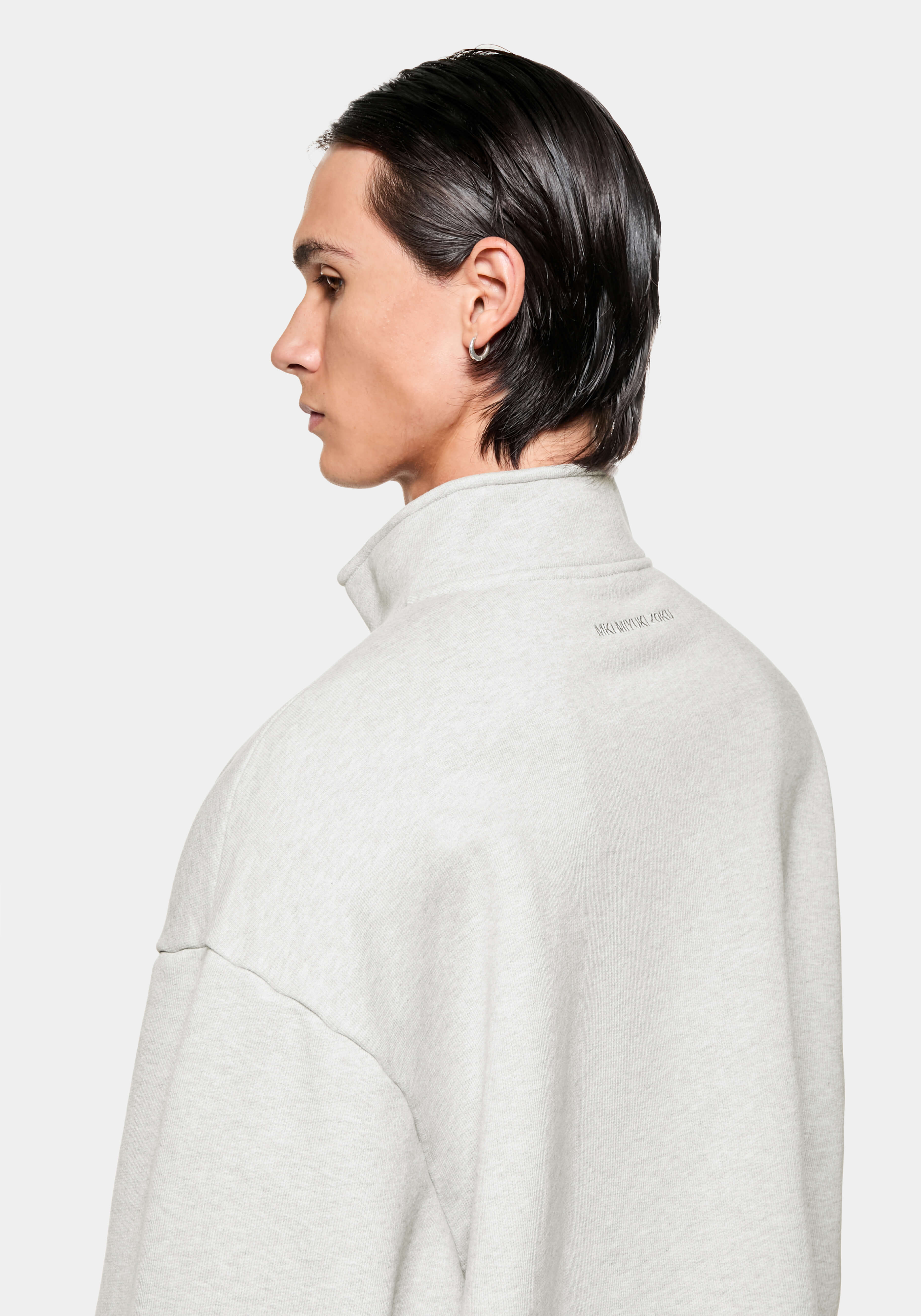 Side profile of the Oatmeal Quarter Zip showing the funnel neck and tonal logo below the collar