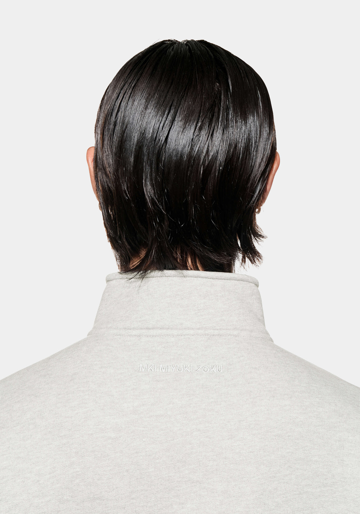 Back view of the funnel neck and tonal MKI MIYUKI ZOKU logo embroidery on the Oatmeal quarter zip