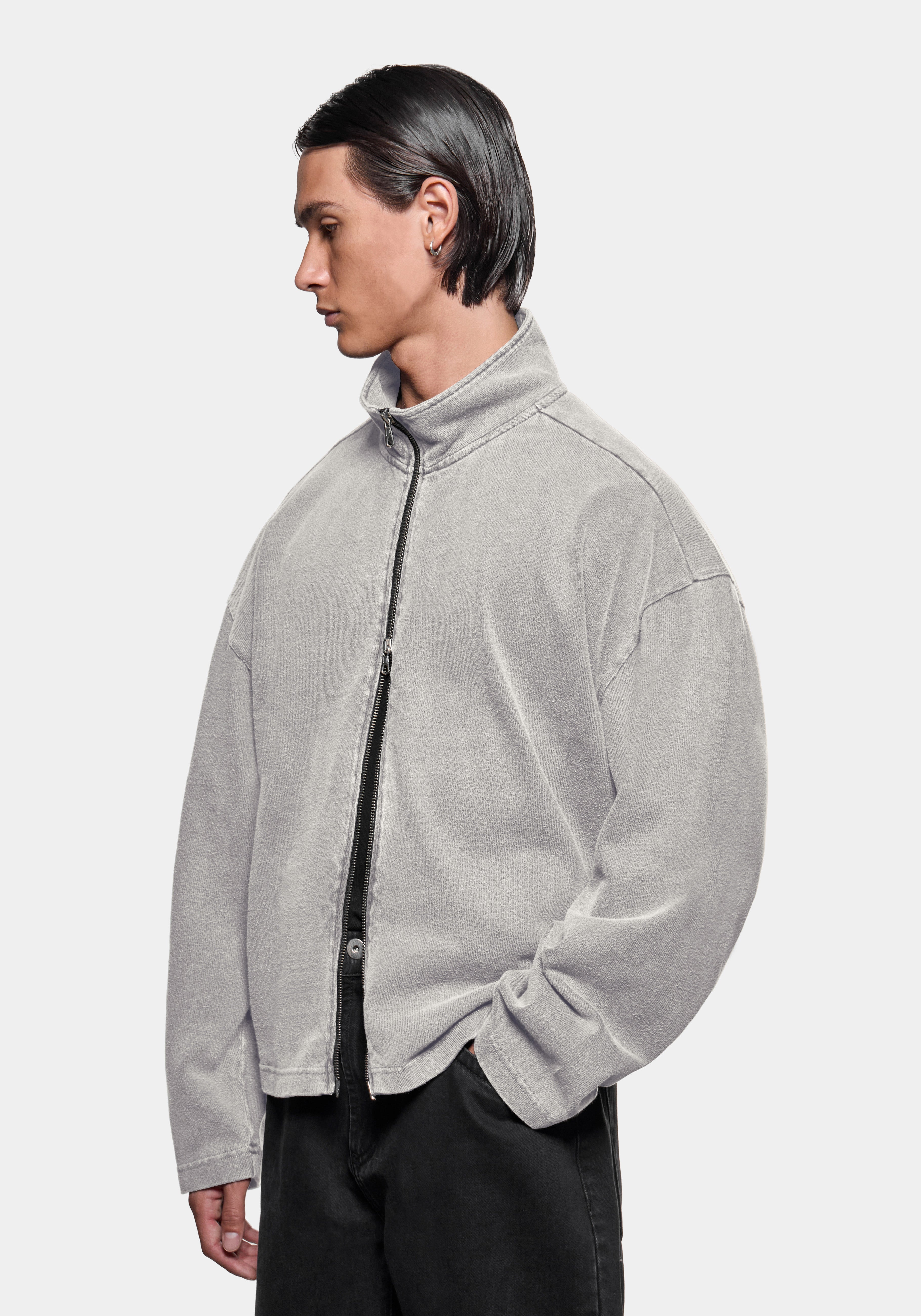 Front view of the track jacket showing the zip funnel neck, styled with black trousers