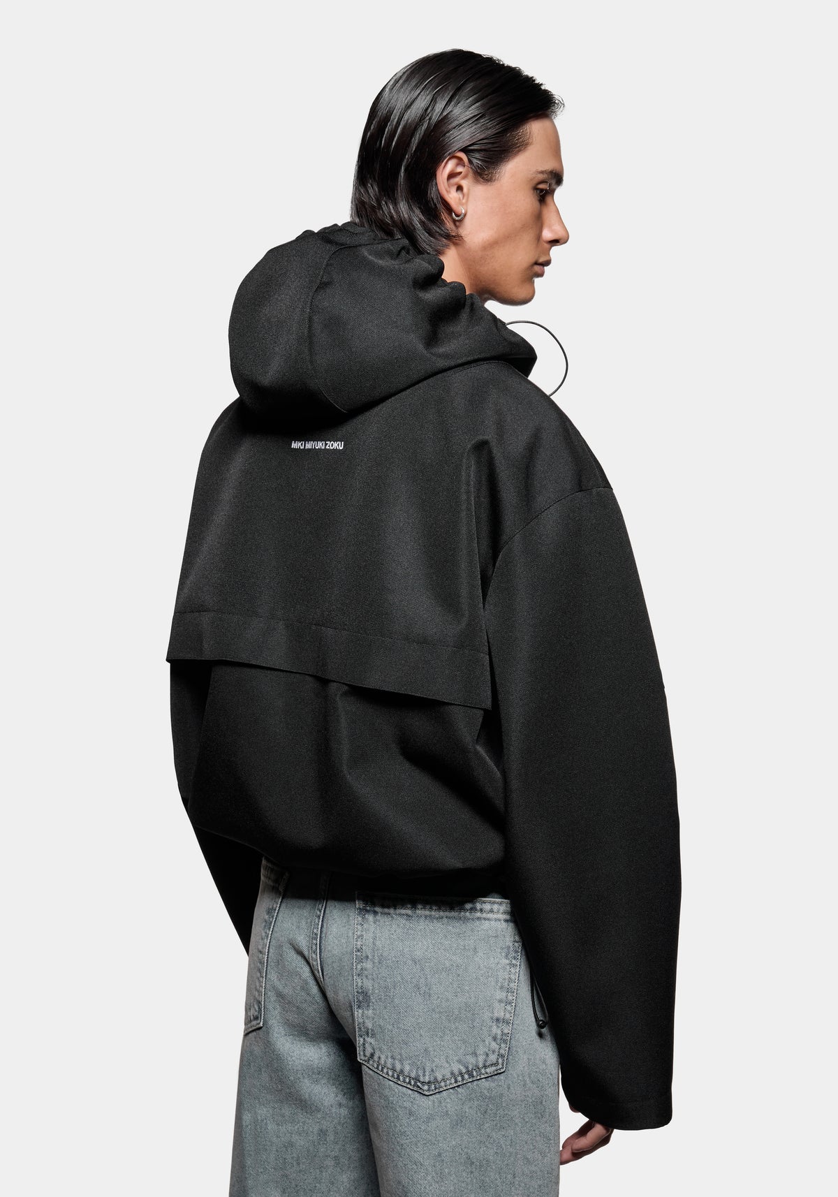 Person wearing a black hooded jacket with MKI MIYUKI ZOKU branding on the back