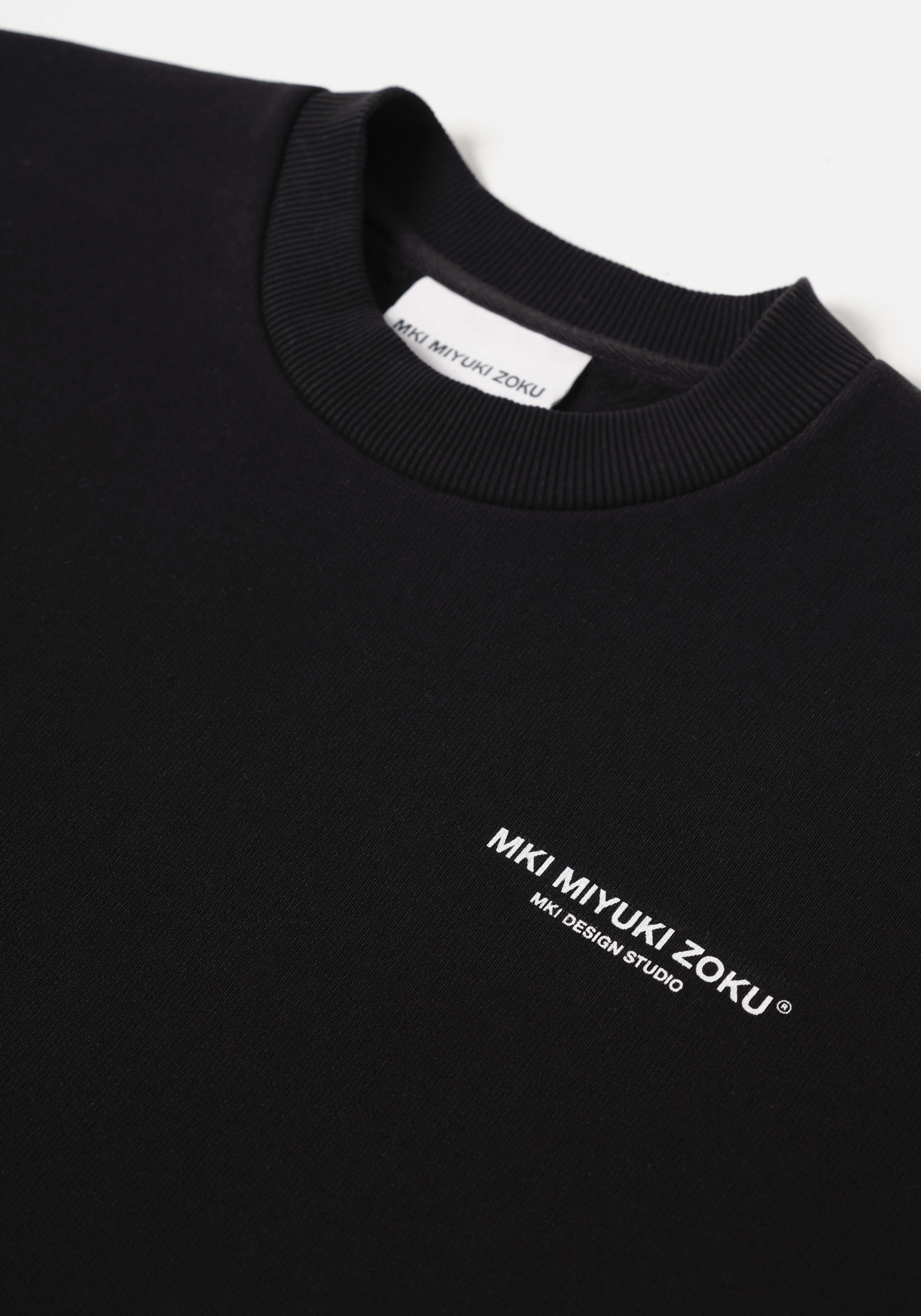 Flat close-up of the contrast Design Studio branding on the chest of the Design Studio Crewneck in Black