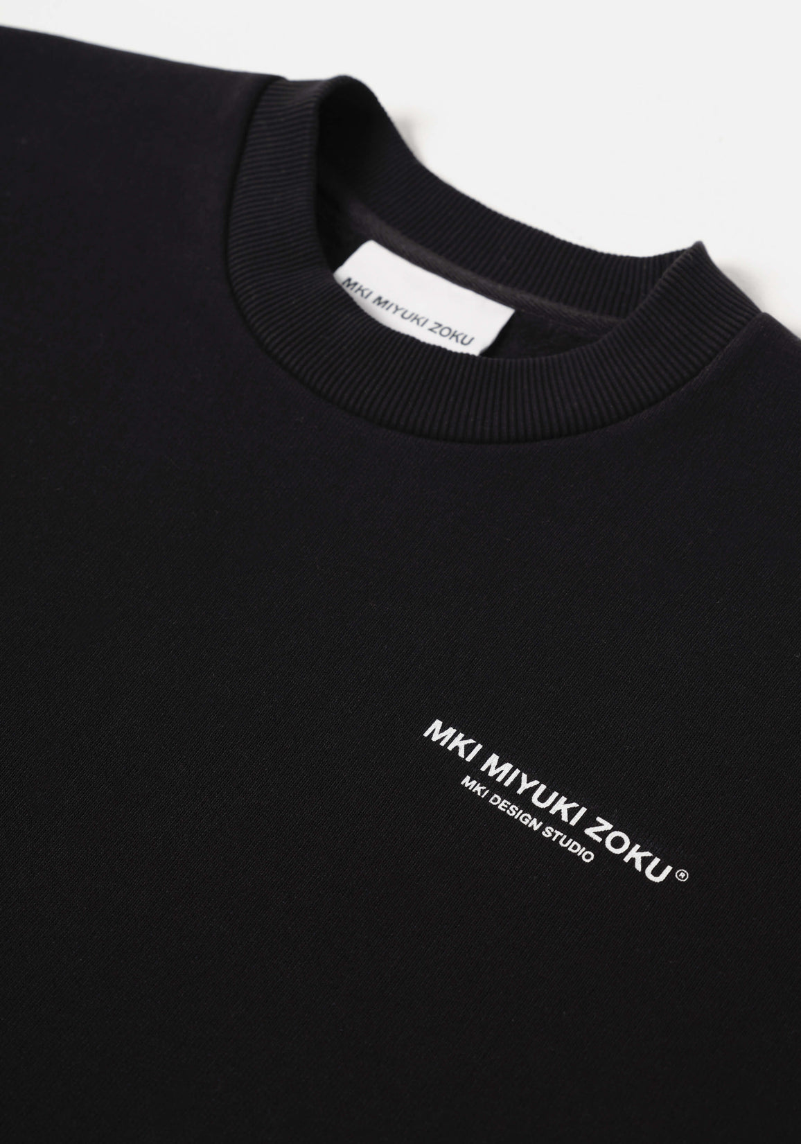 Flat close-up of the contrast Design Studio branding on the chest of the Design Studio Crewneck in Black