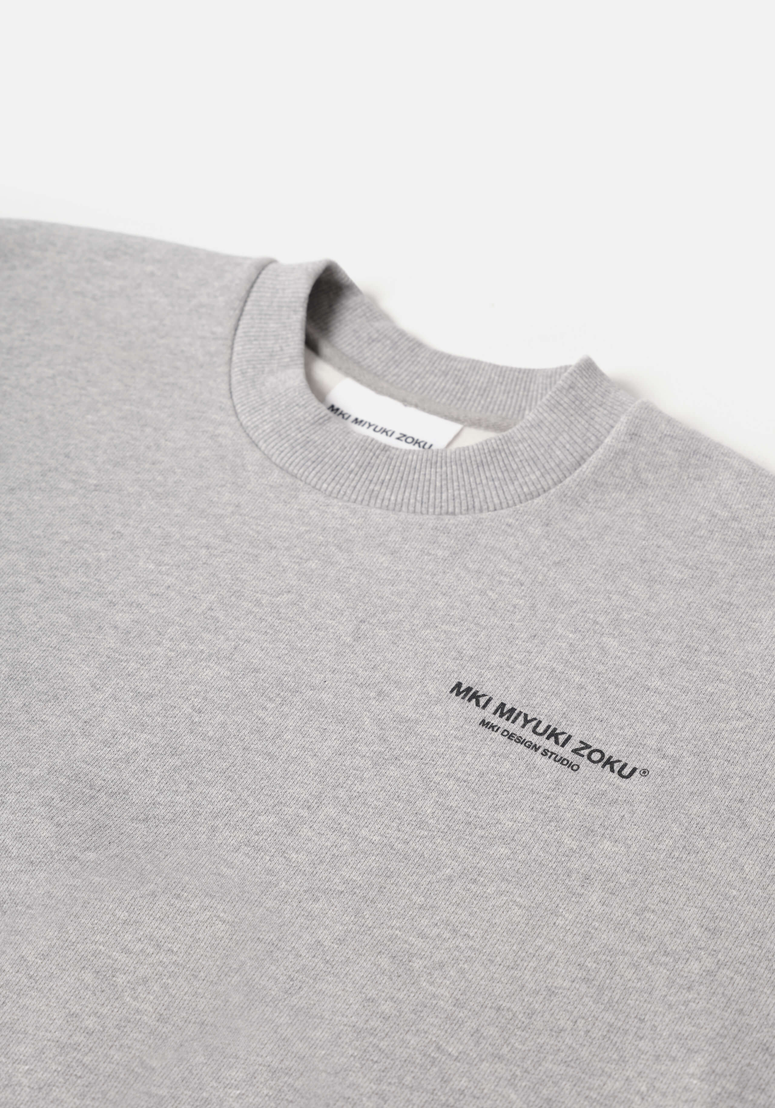 Flat close-up of the contrast Design Studio branding on the chest of the Design Studio Crewneck in Grey