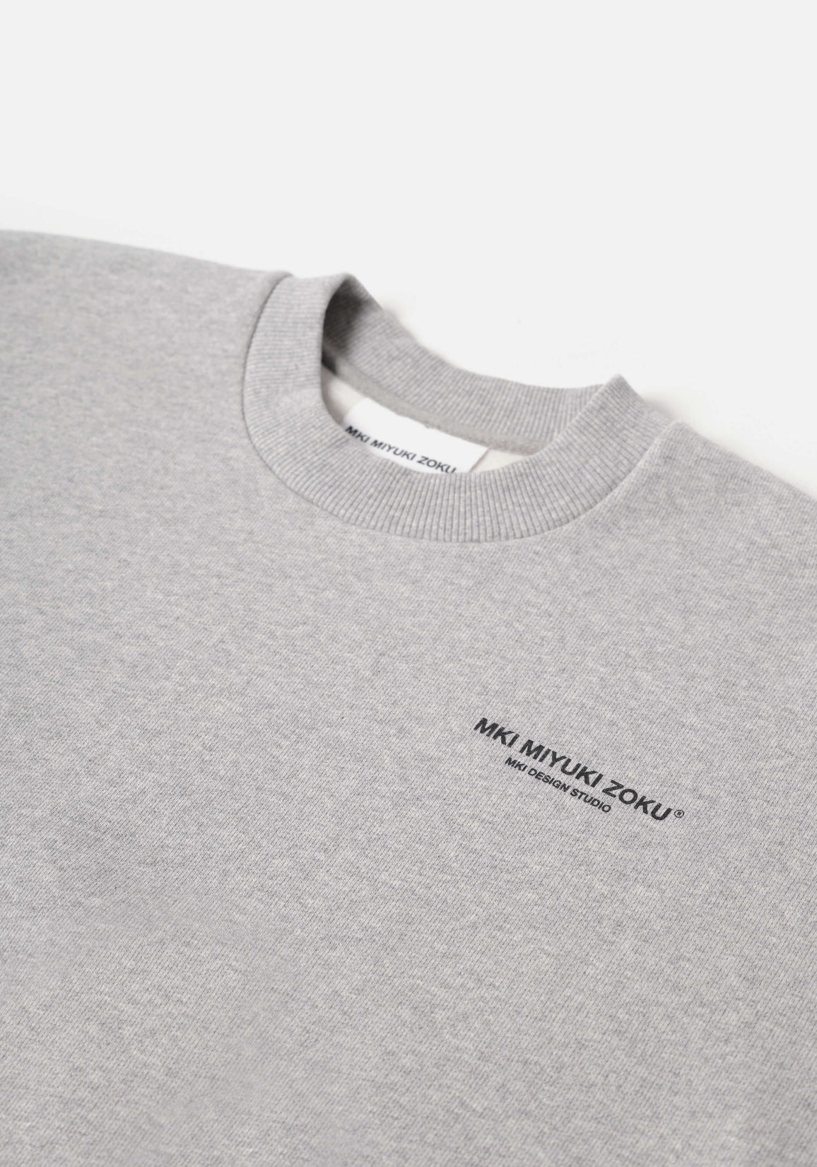 Flat close-up of the contrast Design Studio branding on the chest of the Design Studio Crewneck in Grey