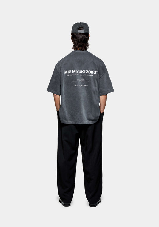 Full rear shot of the men's oversized MKI Design Studio T-shirt in a faded black colourway with design studio branding printed at the back