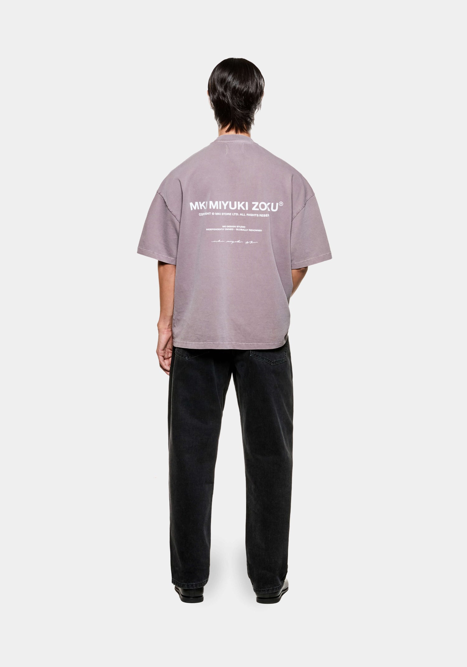 Full rear view of a men's oversized graphic MKI Design Studio t-shirt in a pigment raisin colourway with design studio branding at the back