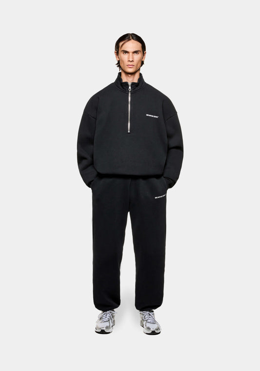 Full front view of a MKI Uniform Jersey Quarter Zip Pullover Top in black with white printed branding in a boxy oversized fit