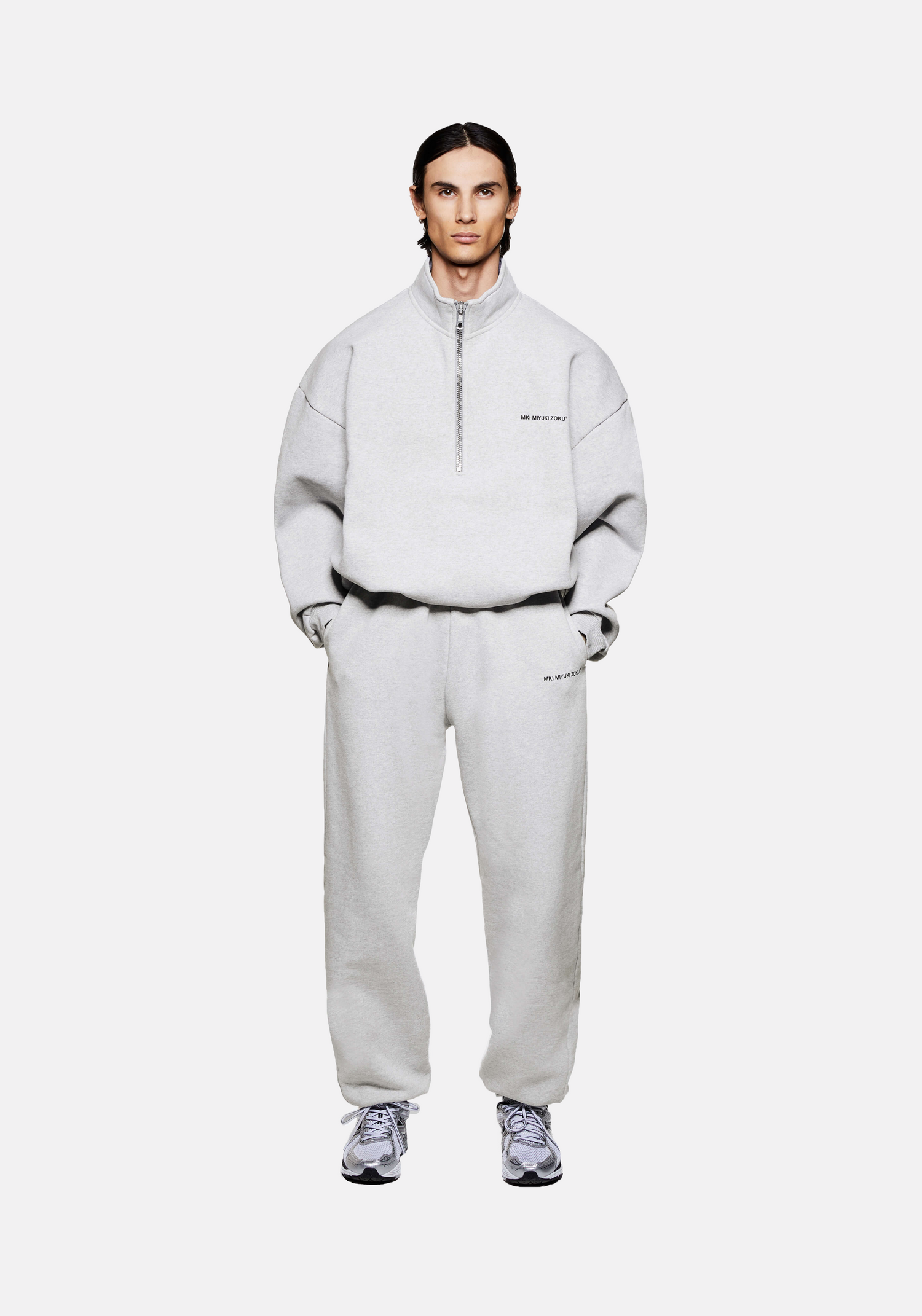 Front view of the MKI Uniform Jersey Quarter Zip Pullover Top in grey with black printed branding in a boxy oversized fit