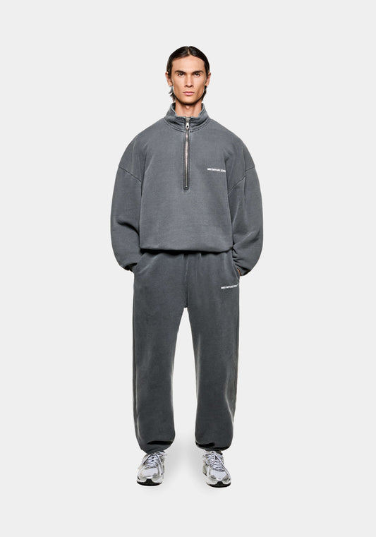 Front view of the MKI Uniform Jersey Quarter Zip Pullover Top in pigment black with white printed branding in a boxy oversized fit